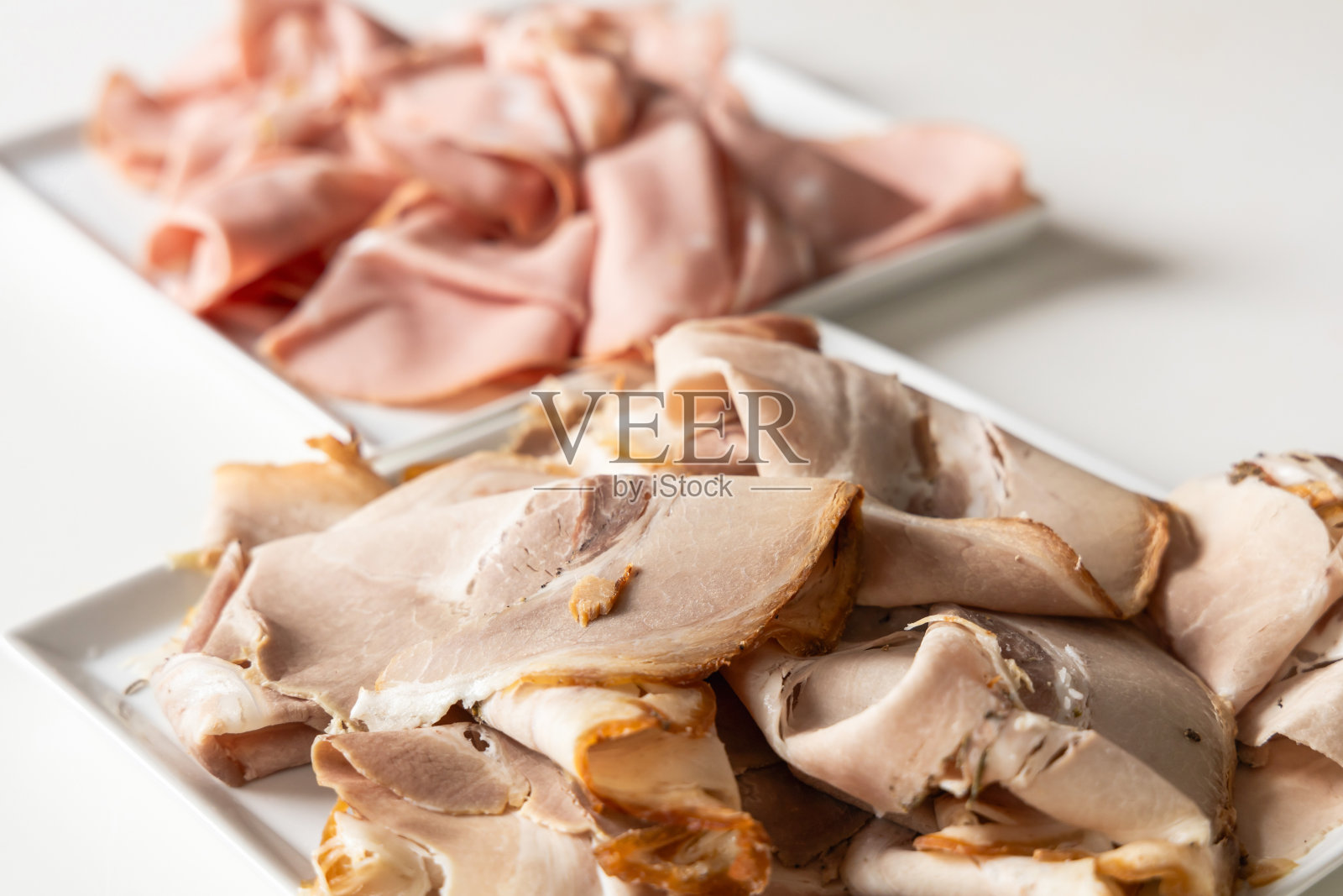 切成薄片的香肠、火腿放在白色盘子里。照片摄影图片