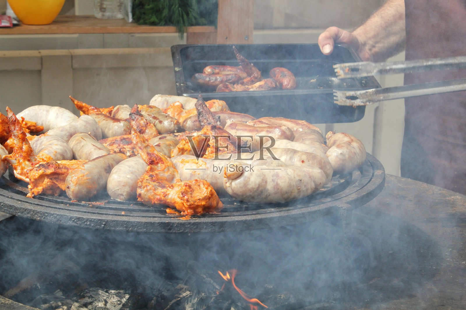 村子里烤架上的煎香肠和鸡翅。在明火上煎肉。烧烤派对在后院的乡村小屋。街头美食节。户外家庭烹饪。野餐的时间照片摄影图片
