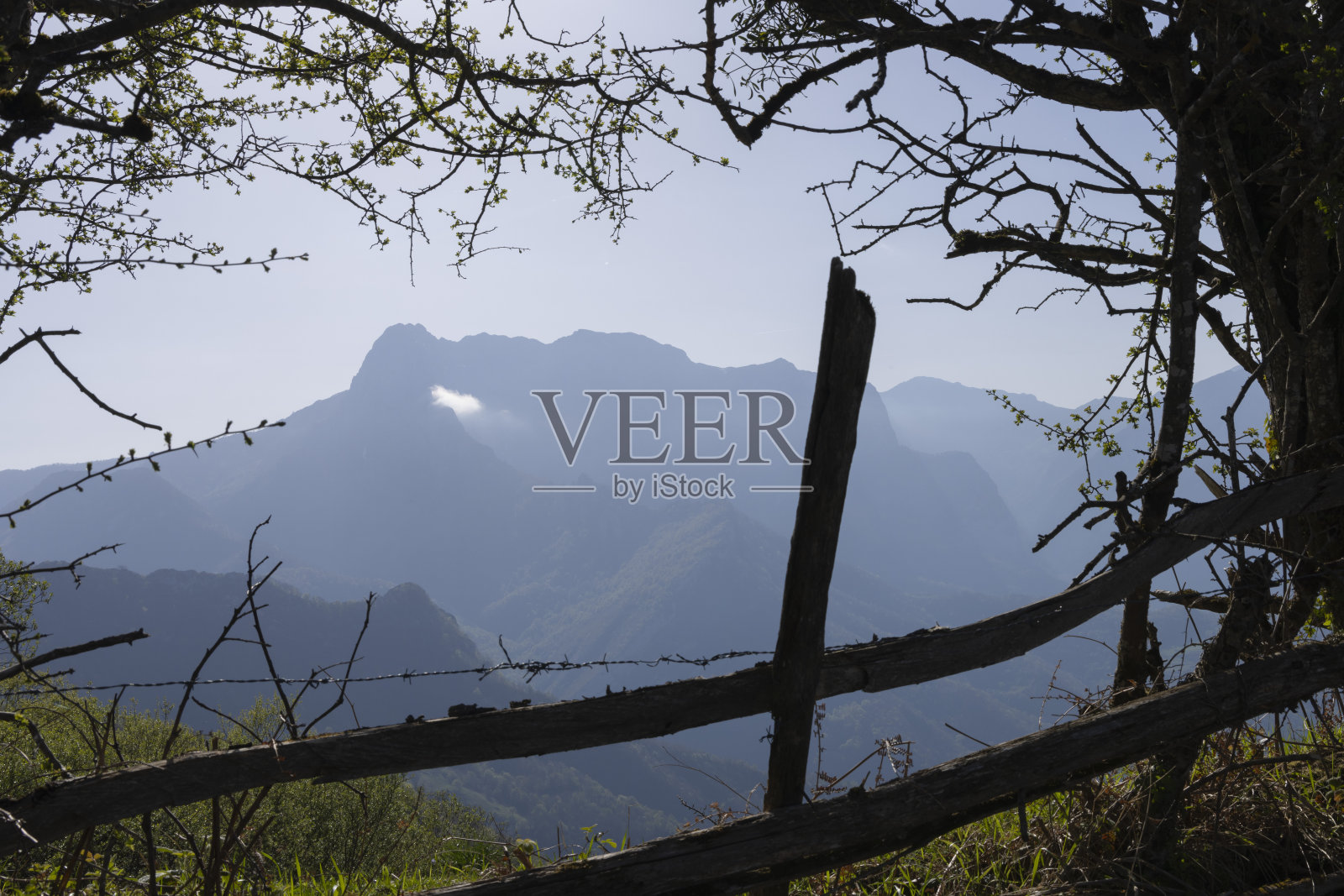 在一个阳光明媚的春日，有山峰和云的山景，绿色的植被和蓝色的天空照片摄影图片