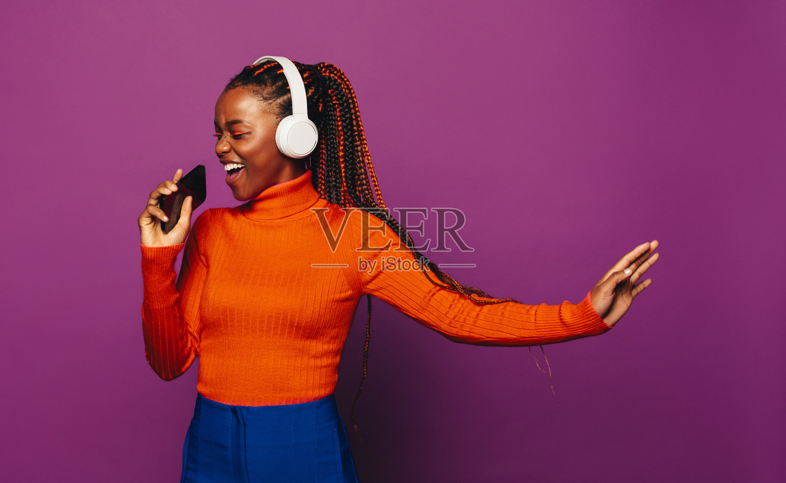 快乐的女孩唱歌和流媒体音乐与耳机在紫色的背景照片摄影图片