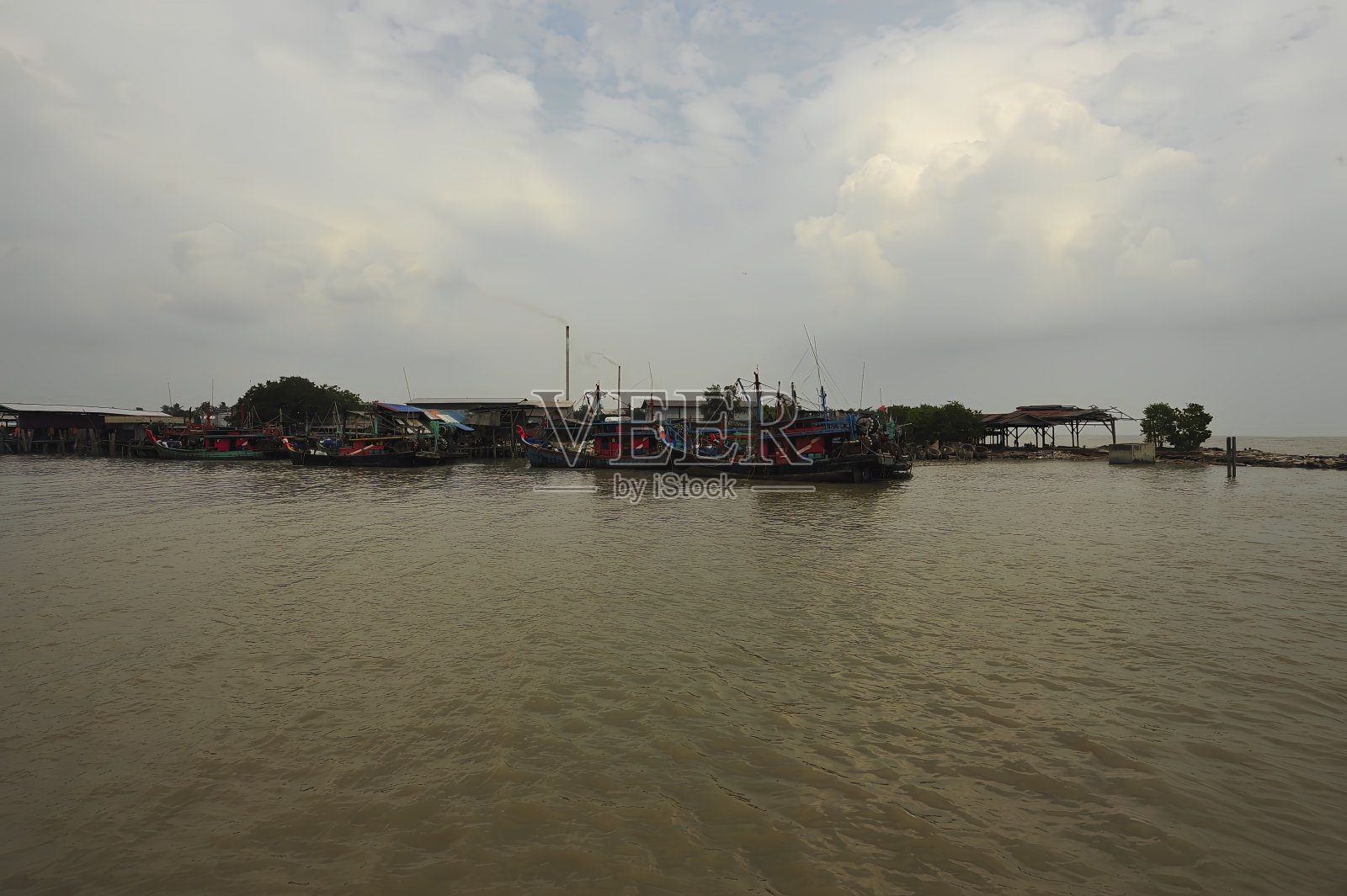 绿色和红色的渔船在多云的海面上航行照片摄影图片