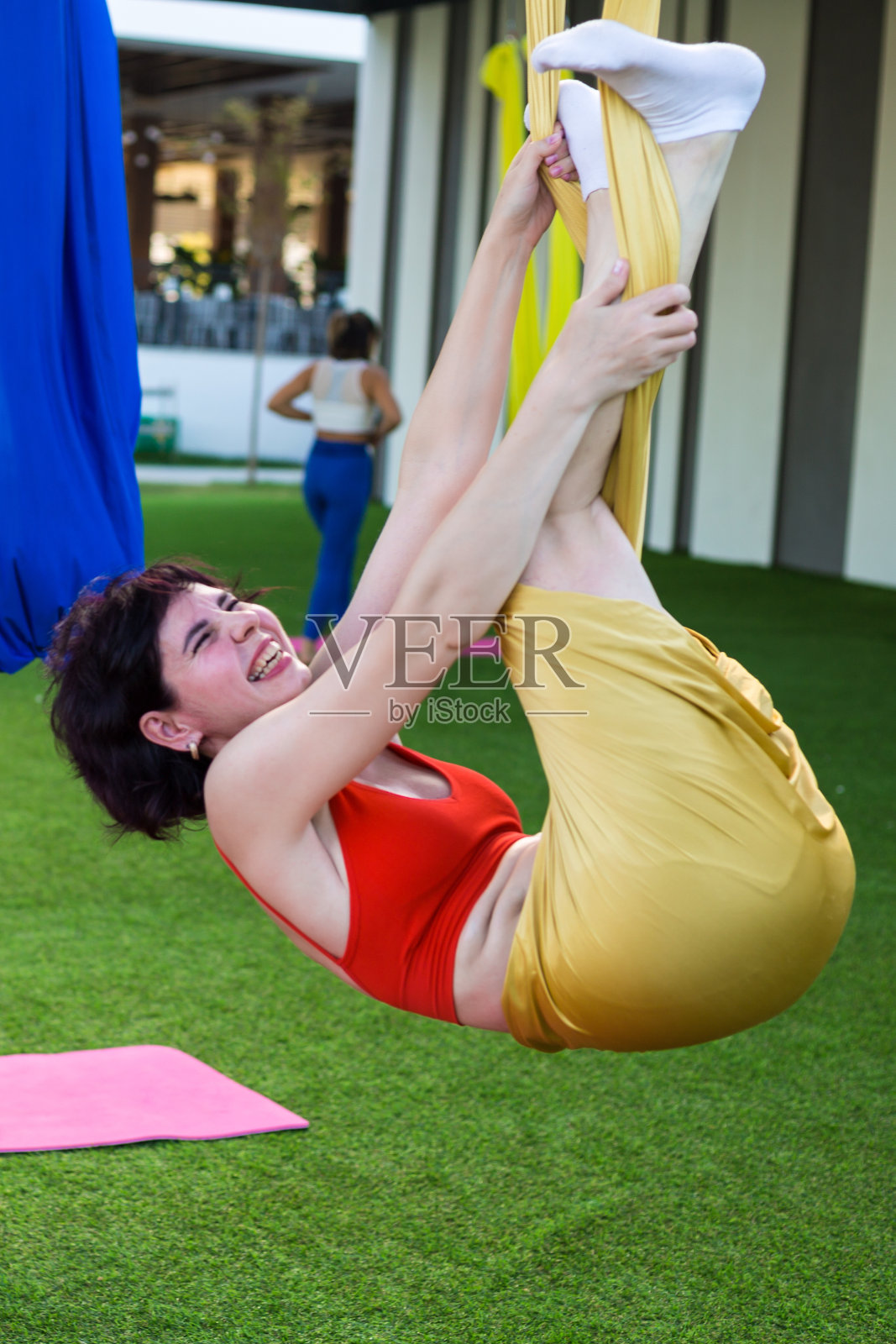 一个女孩在空中瑜伽时做了一个有趣的姿势，被织物缠住了照片摄影图片