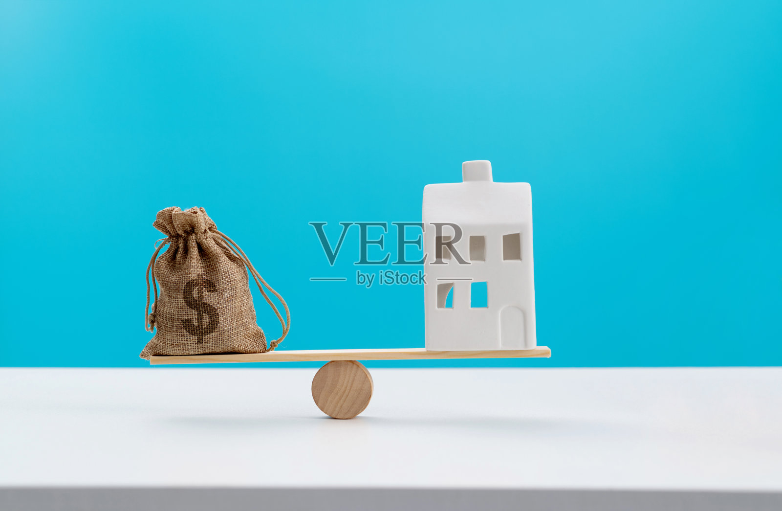 带着钱袋和样板房的木制跷跷板照片摄影图片