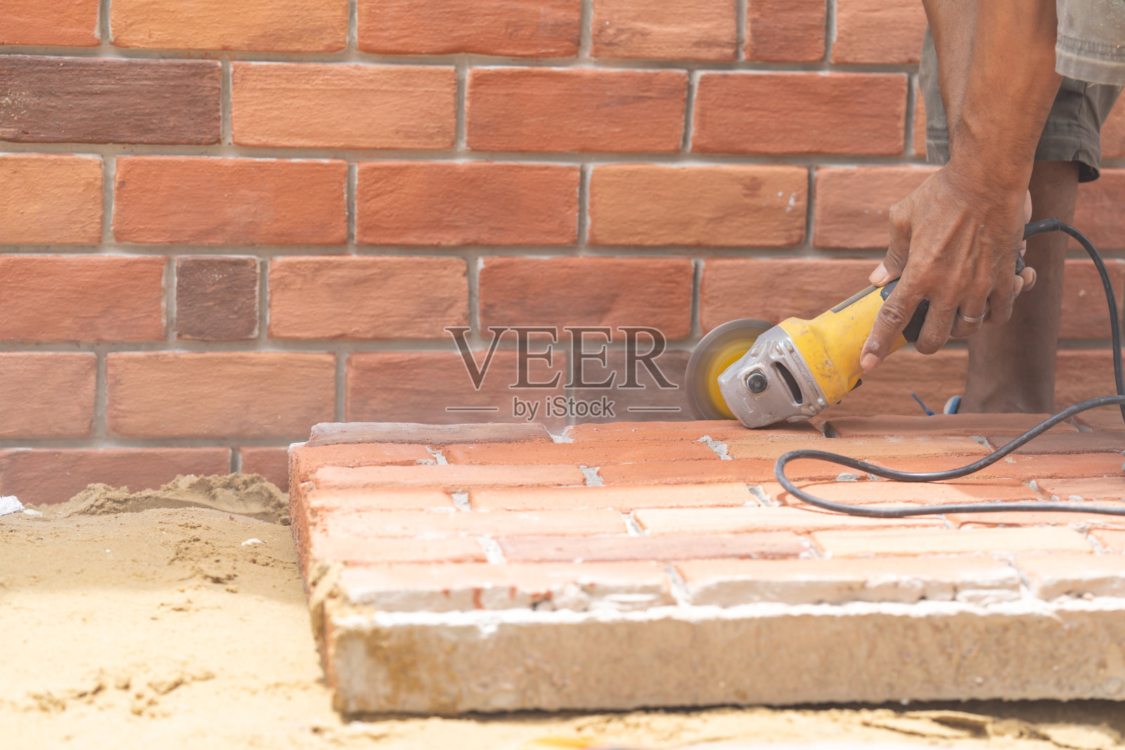 近距离工人拿着手持式锯床切割墙安装用的砖泡沫板。照片摄影图片