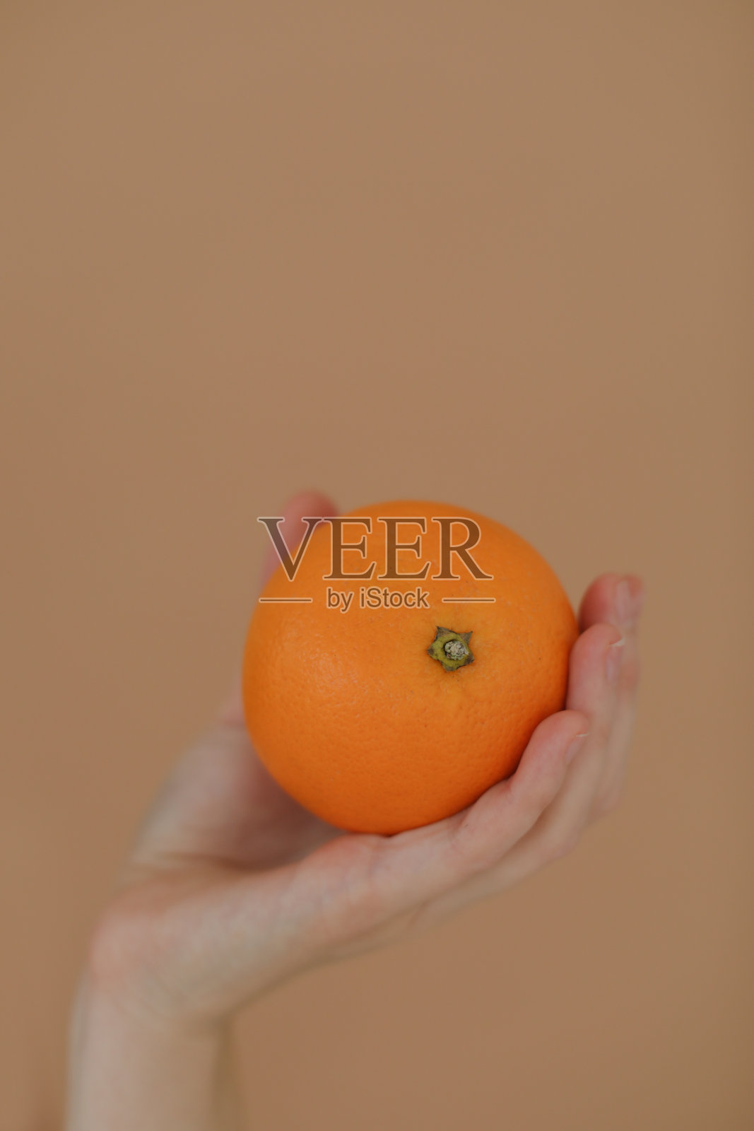 手里拿着一个新鲜的热带橘子。一个女人手里拿着一个橘子，背景是孤立的黄色。女孩一手拿着柑橘照片摄影图片