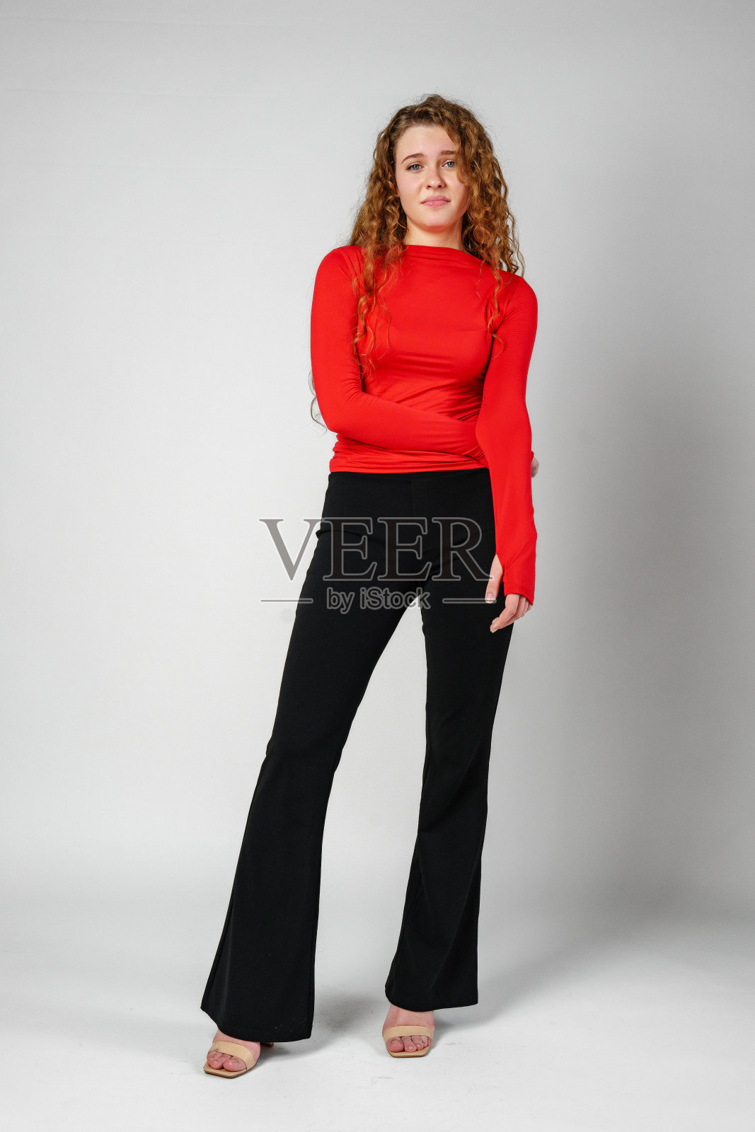 一头卷发的女人站在灰色背景上照片摄影图片