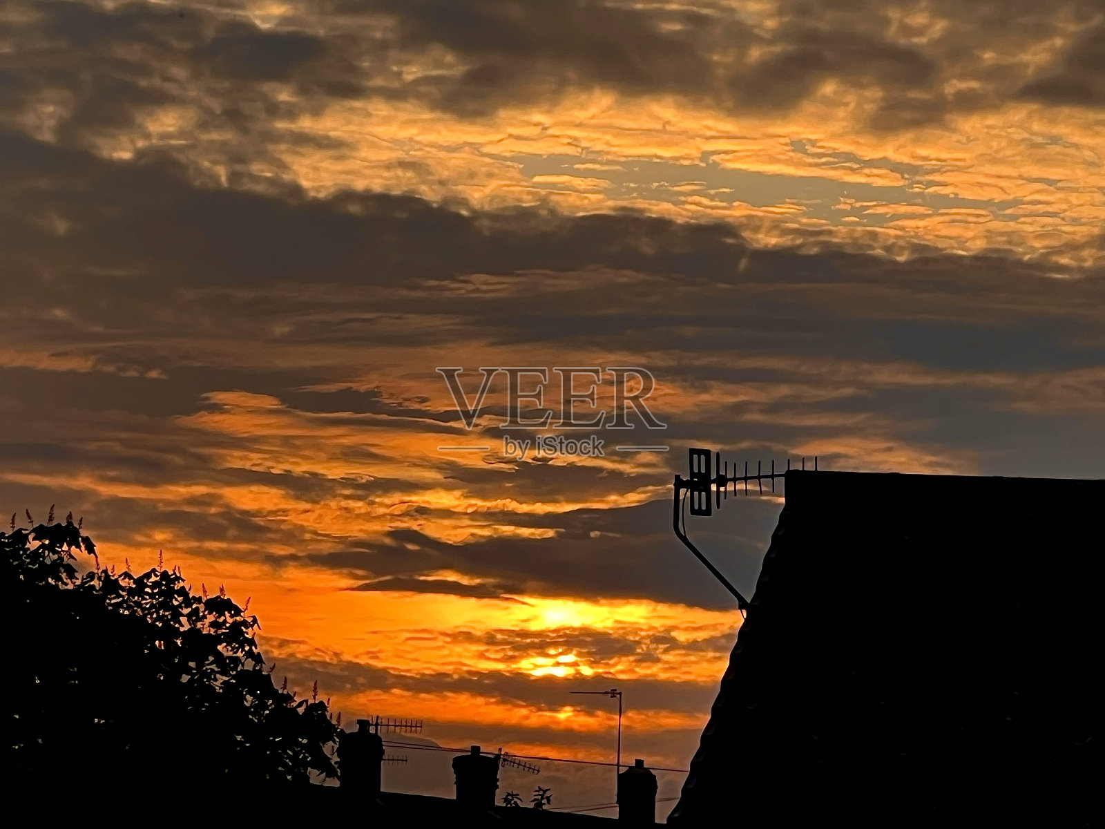 泰恩河畔纽卡斯尔，夕阳西下，城市里有房子、树木、烟囱和电视天线的剪影照片摄影图片