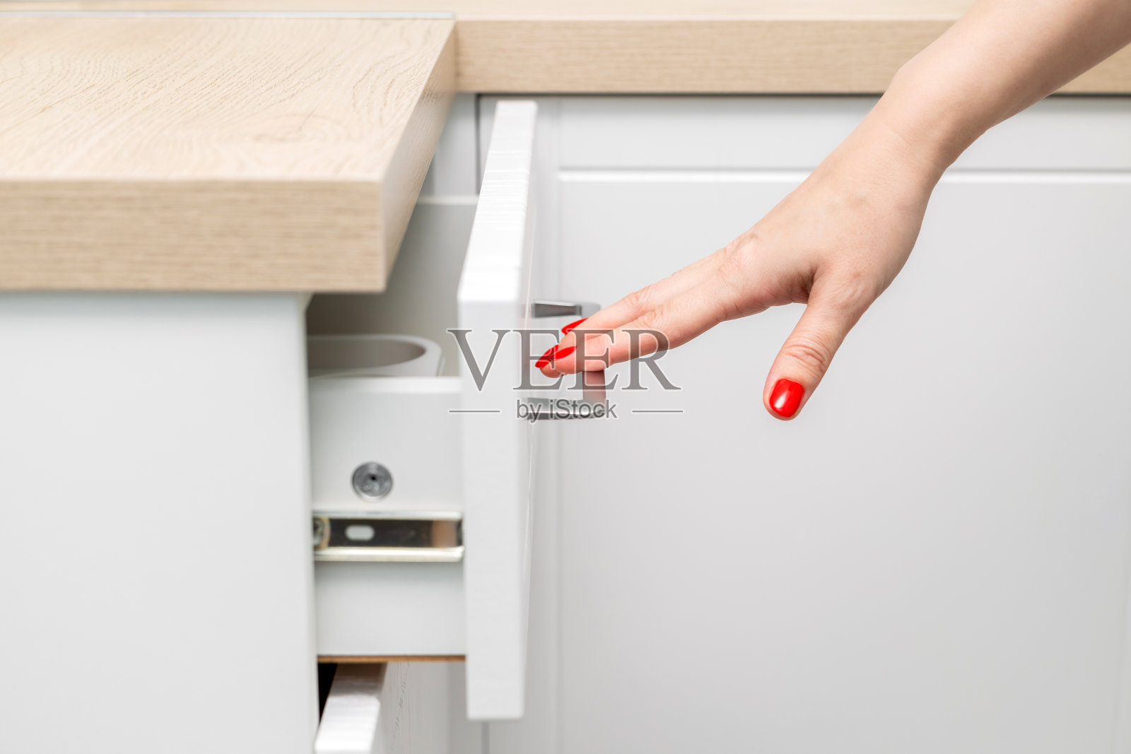 修剪指甲的女人的手打开了厨房橱柜的抽屉照片摄影图片
