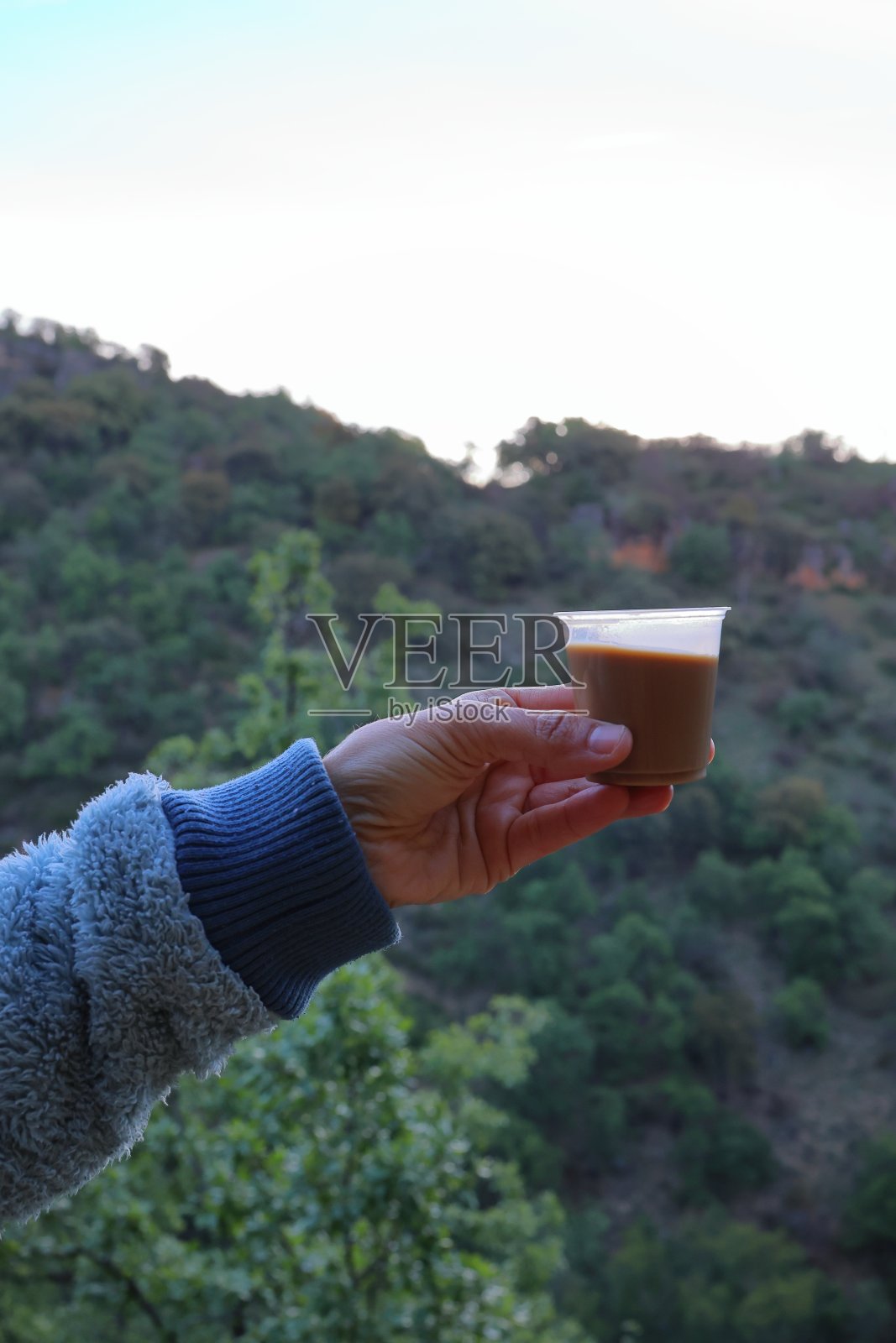 在有山有树的风景中，端着一杯咖啡举杯照片摄影图片