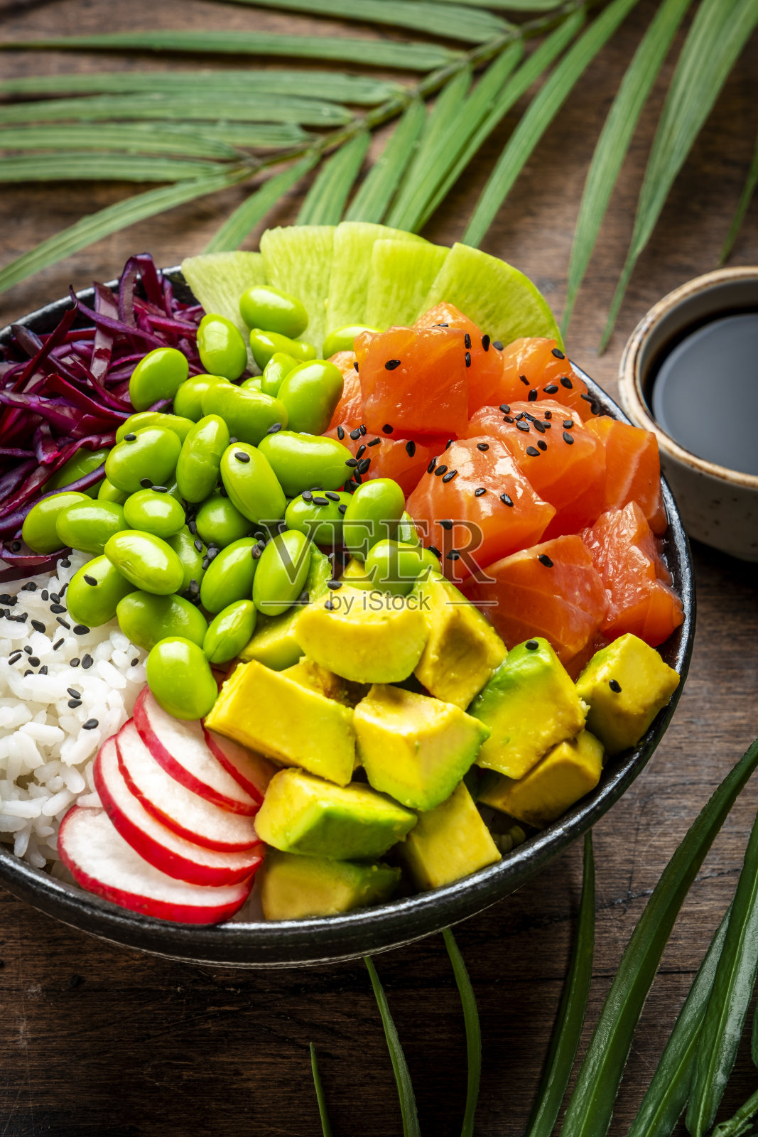 以鲑鱼、牛油果、萝卜、卷心菜、豆类、芝麻和米饭为食的均衡饮食，木桌背景，俯视图照片摄影图片