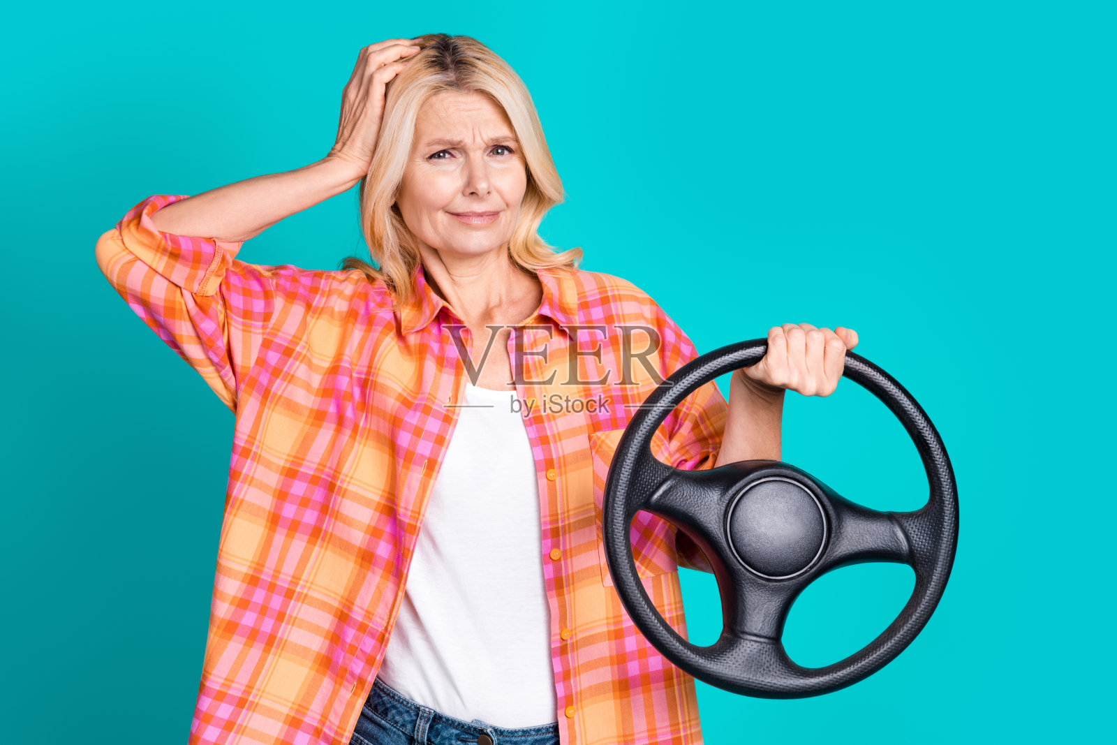照片困惑的人与金发穿着格子衬衫持有方向盘手臂在头上孤立的蓝绿色背景照片摄影图片