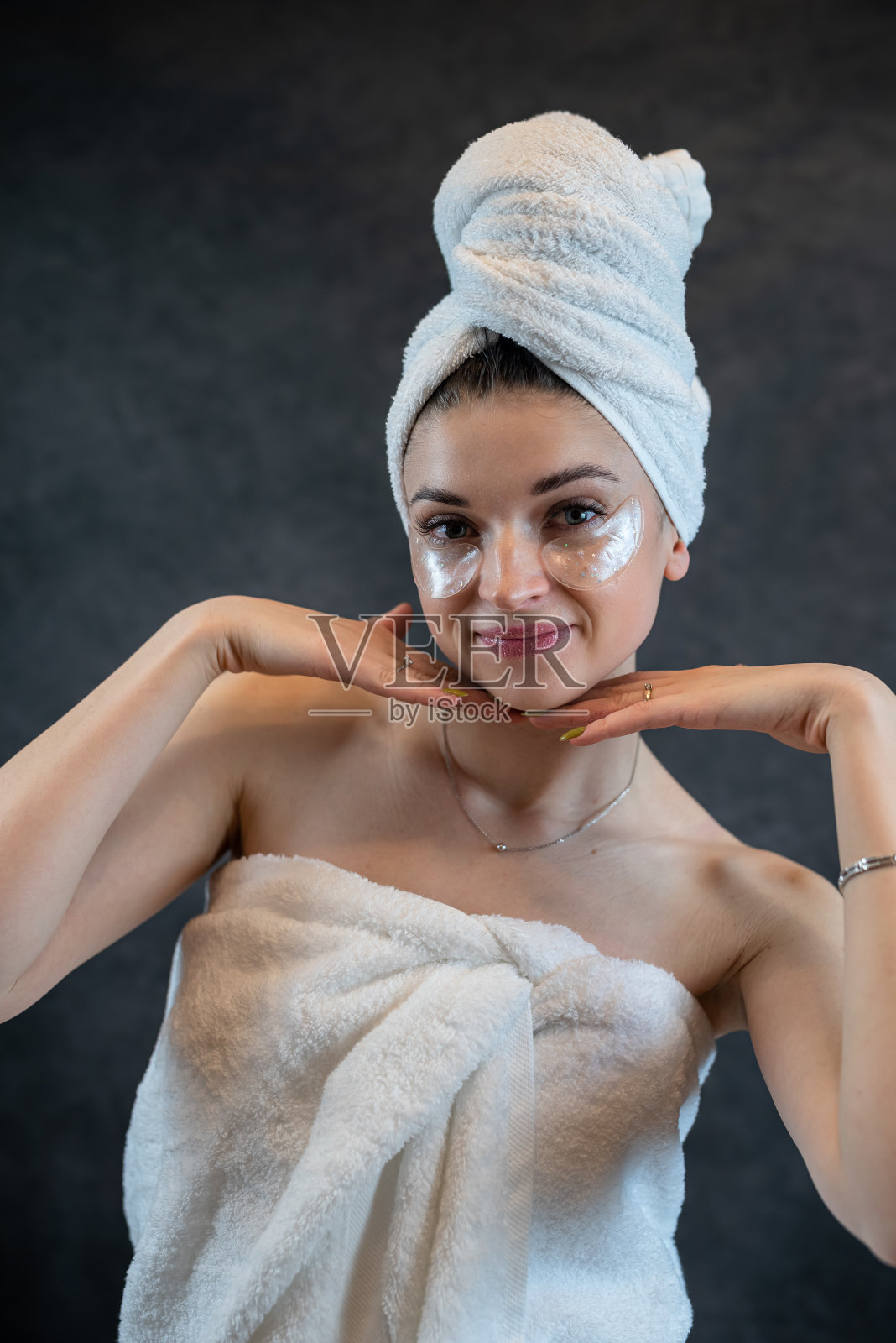 开朗的女士用白色毛巾涂抹胶原蛋白贴片，使眼部皮肤光滑，隔绝了黑色照片摄影图片