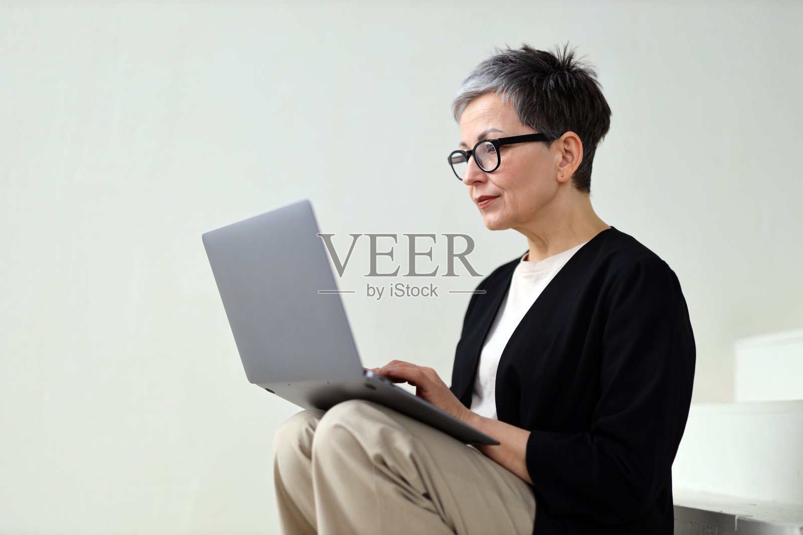 一个成熟的女人在家里用笔记本电脑工作，享受着现代科技带来的舒适。照片摄影图片