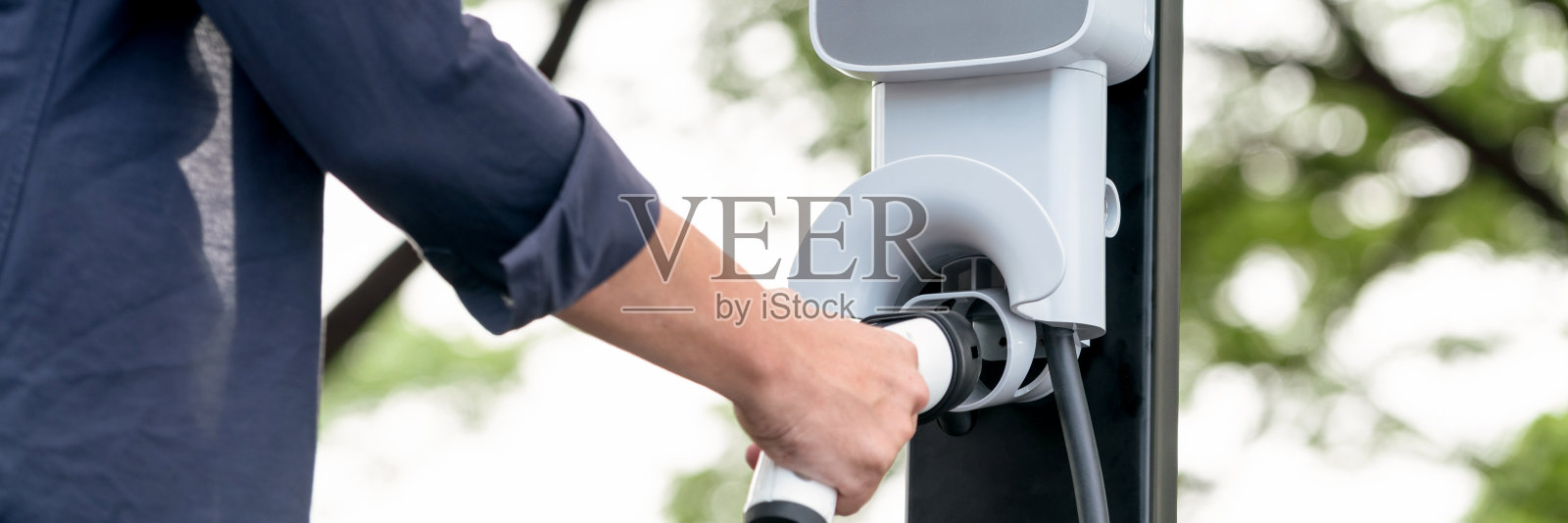 一名男子在旅途中给电动汽车充电。高举照片摄影图片