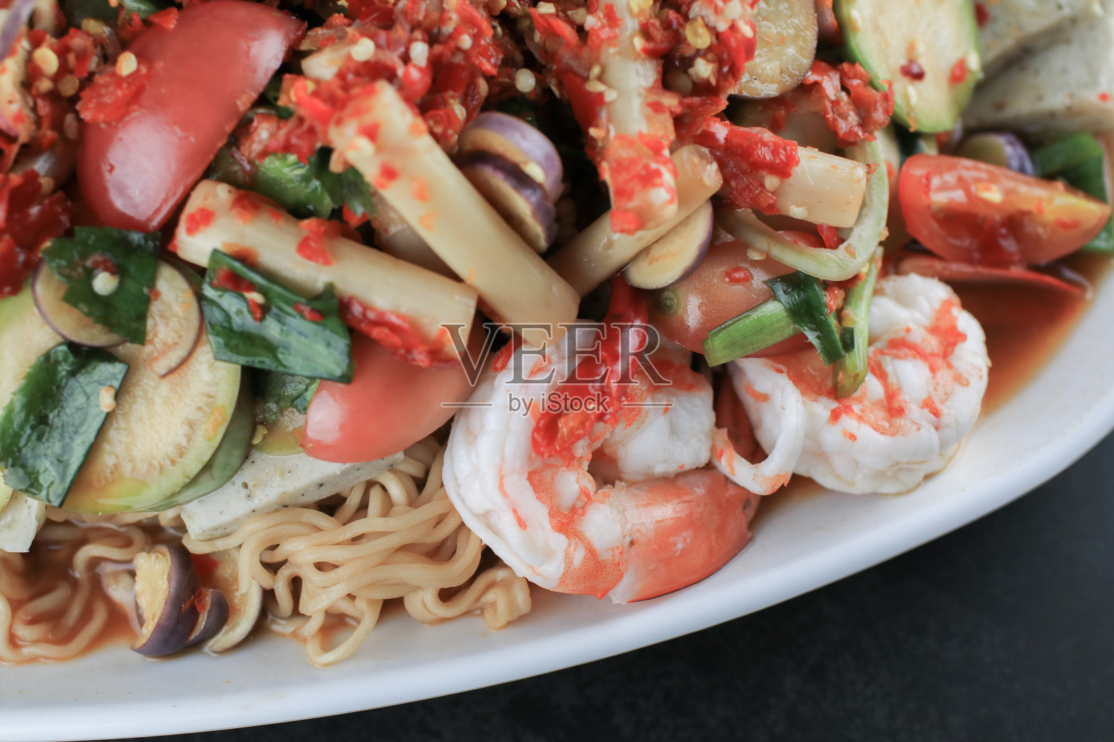 方便面辣沙拉，虾和蔬菜在黑色的桌子上。泰国传统美食百胜妈麻辣照片摄影图片