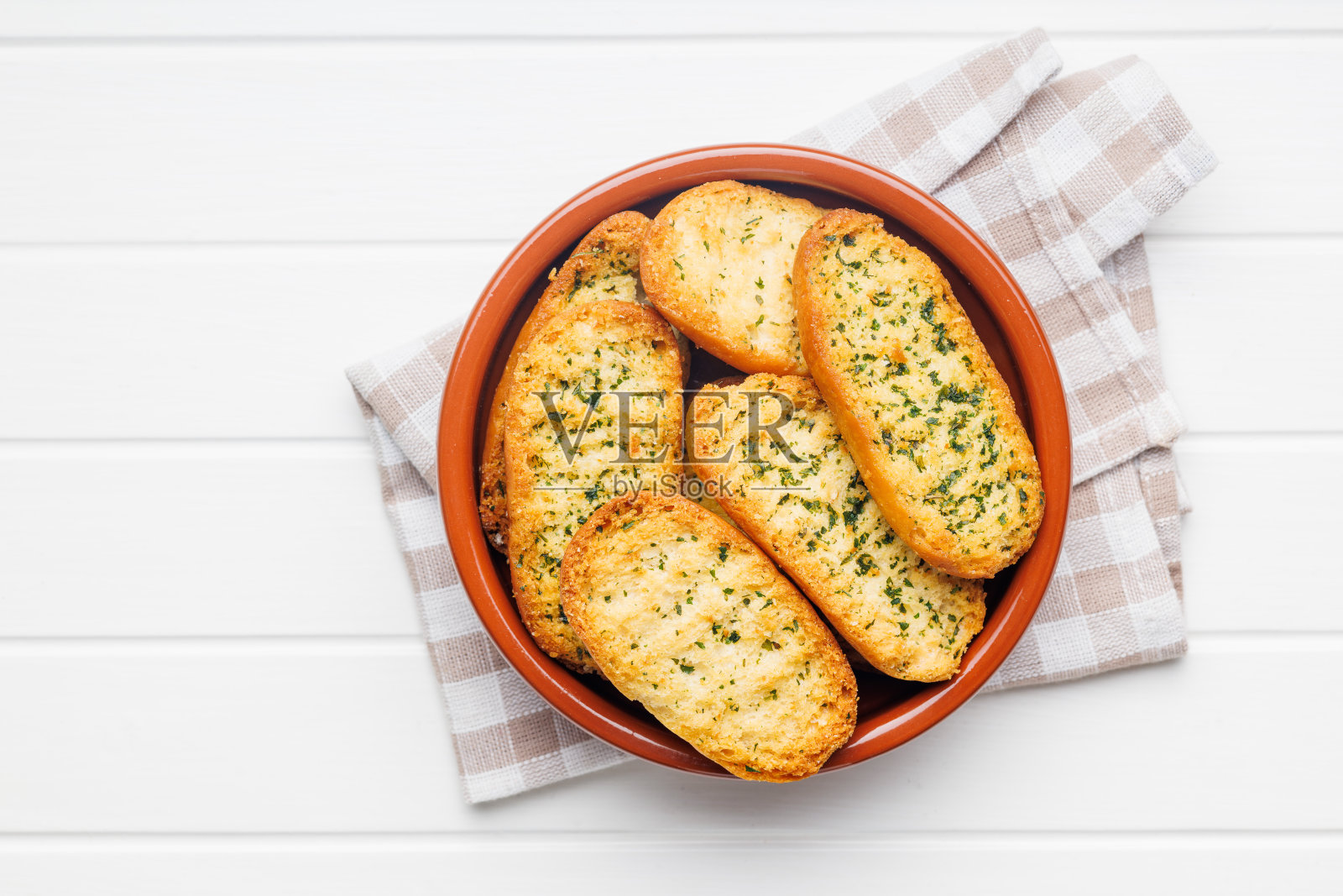 碗里的蒜香脆面包片配上香草。照片摄影图片