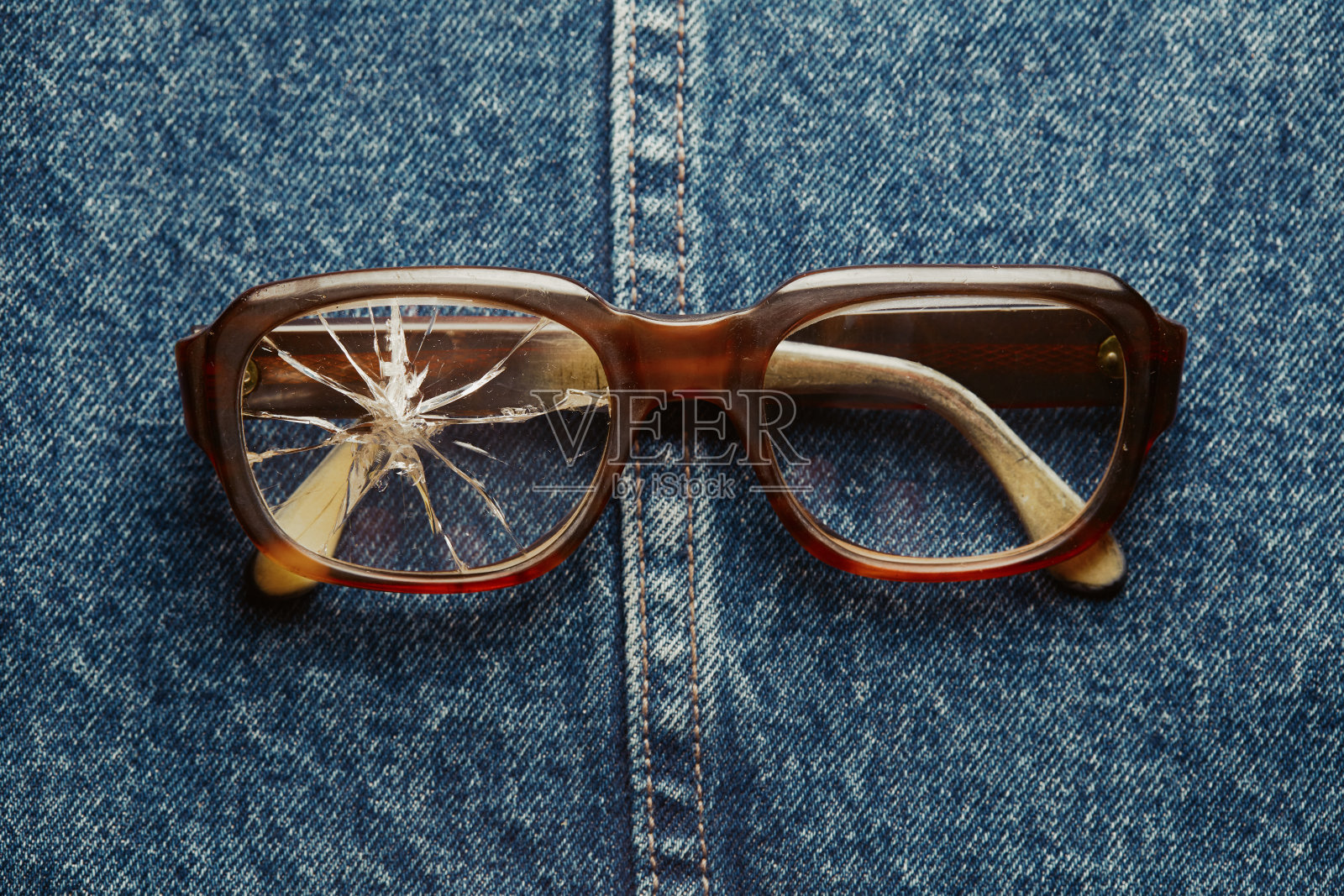 牛仔布背景上破损的老式眼镜照片摄影图片
