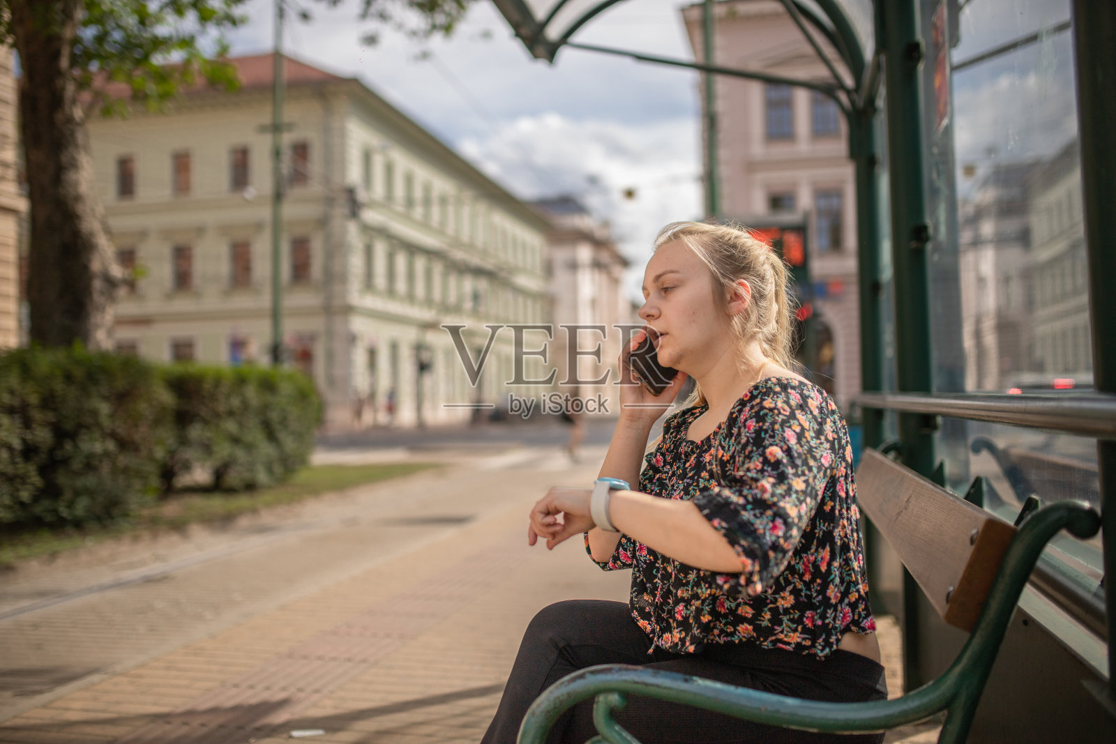 年轻女子坐在电车站用智能手机聊天照片摄影图片