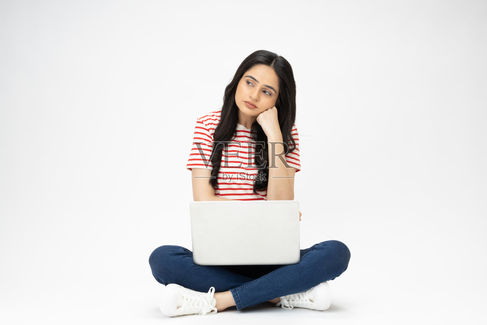 美丽的女孩坐在地板上使用笔记本电脑的全尺寸照片与现代服装隔离在白色背景股票照片照片摄影图片