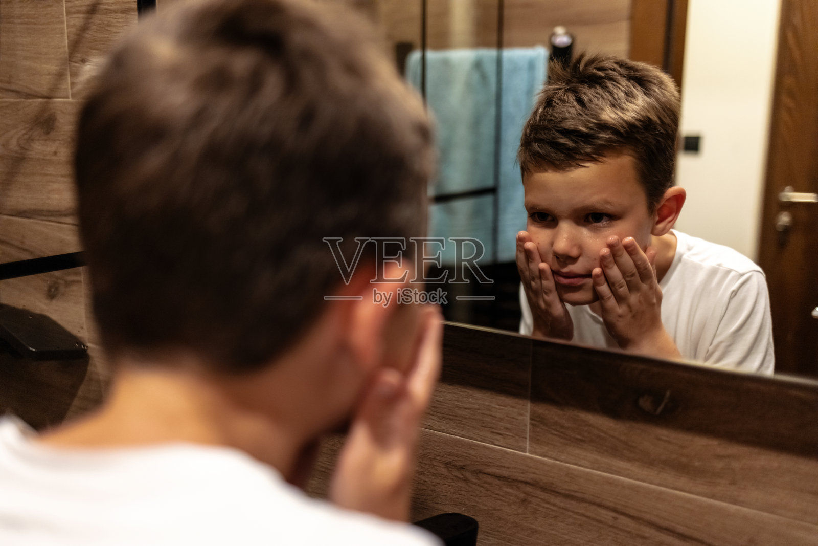 一个可爱的小男孩在家里浴室的水龙头边洗手和嘴。照片摄影图片