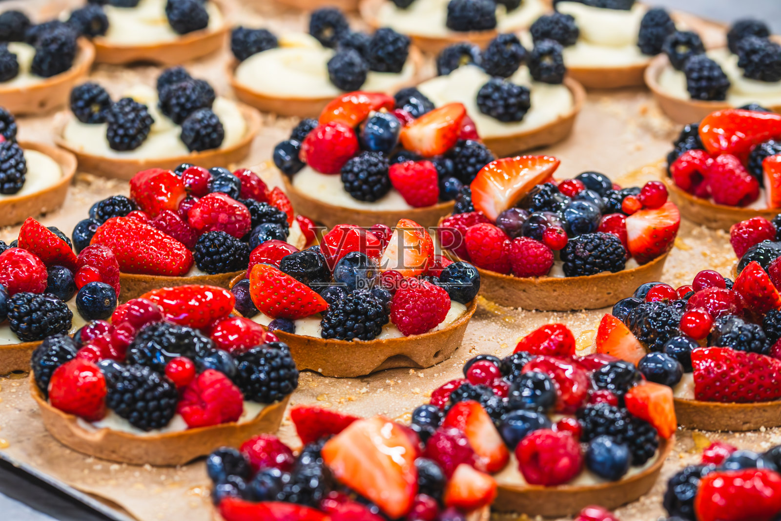 托盘上有覆盆子，黑莓，草莓，醋栗，蓝莓的蛋挞照片摄影图片