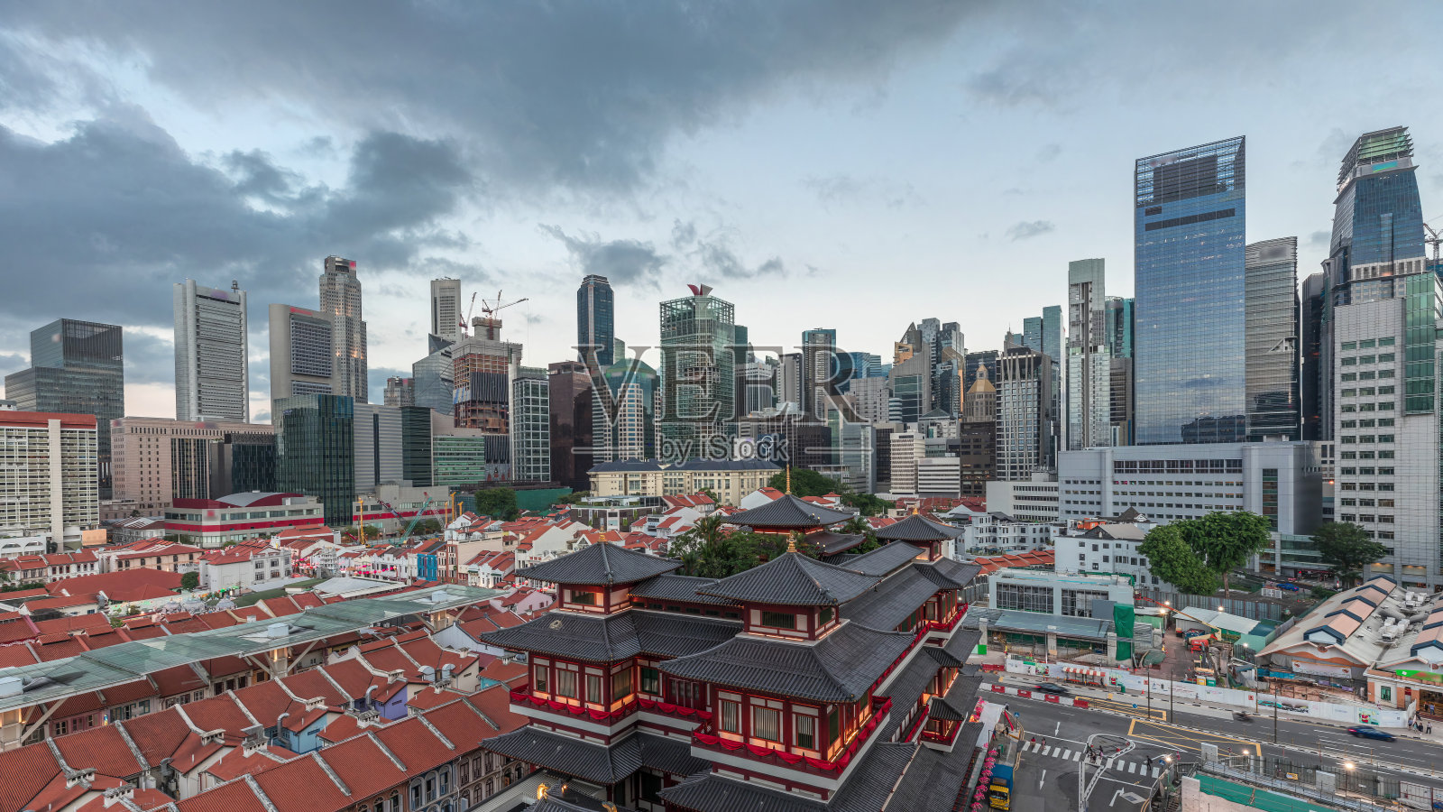 在新加坡唐人街，佛牙寺在白天到晚上的时间间隔中活跃起来，背景是城市的天际线。照片摄影图片