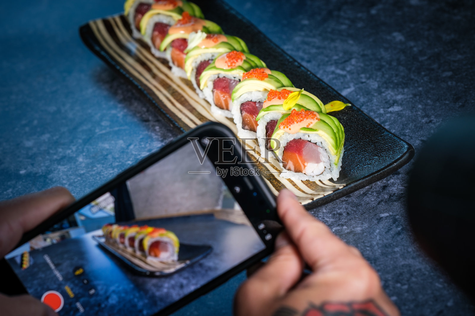 面目全非的人用智能手机拍托盘上的寿司卷照片摄影图片