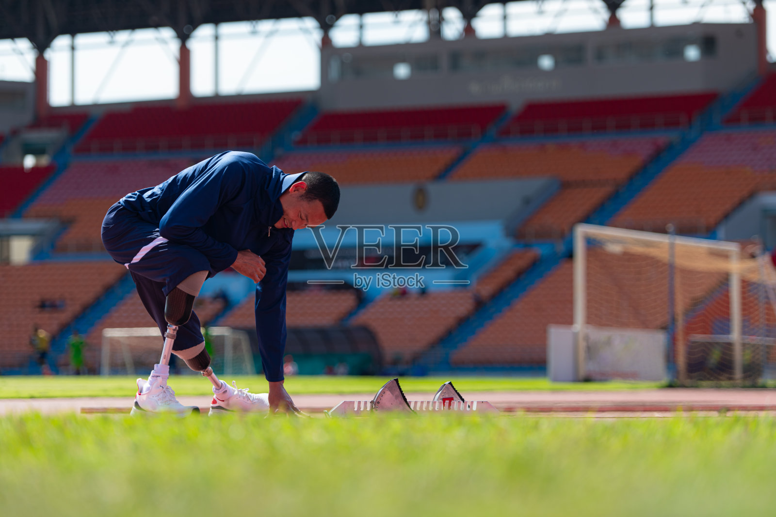 残疾运动员在体育场跑道上跑步前伸展和热身照片摄影图片