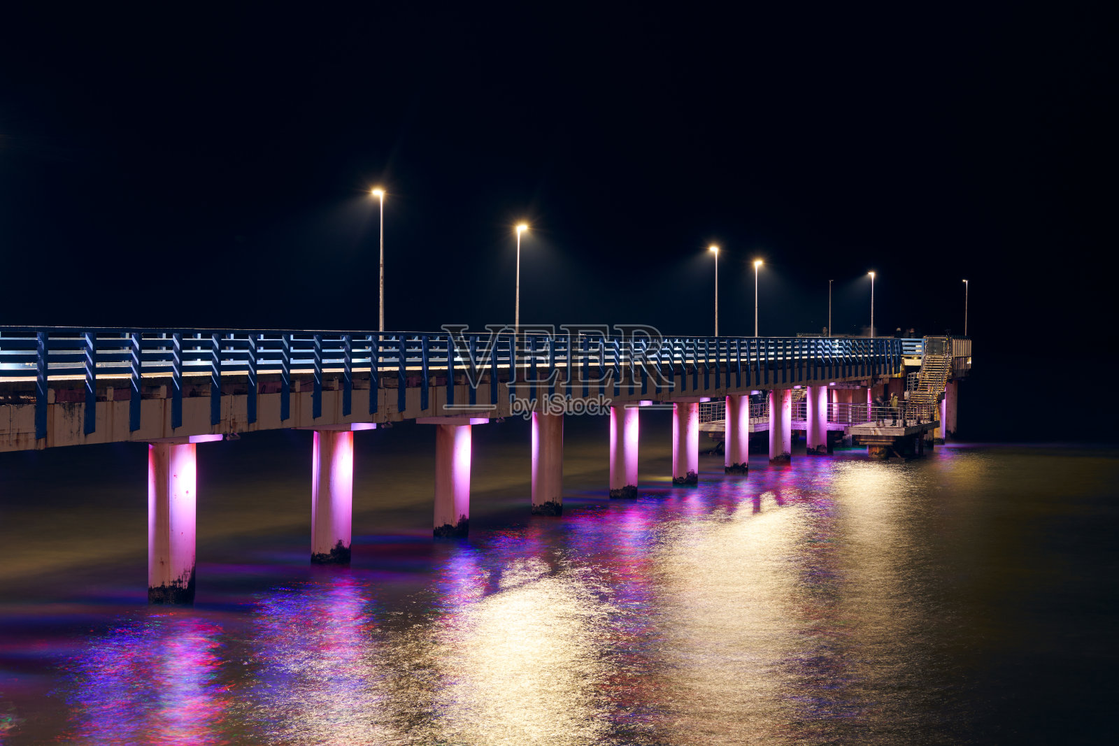 夜晚，五彩缤纷的灯光点缀着海上码头，象征着魅力和诱惑照片摄影图片