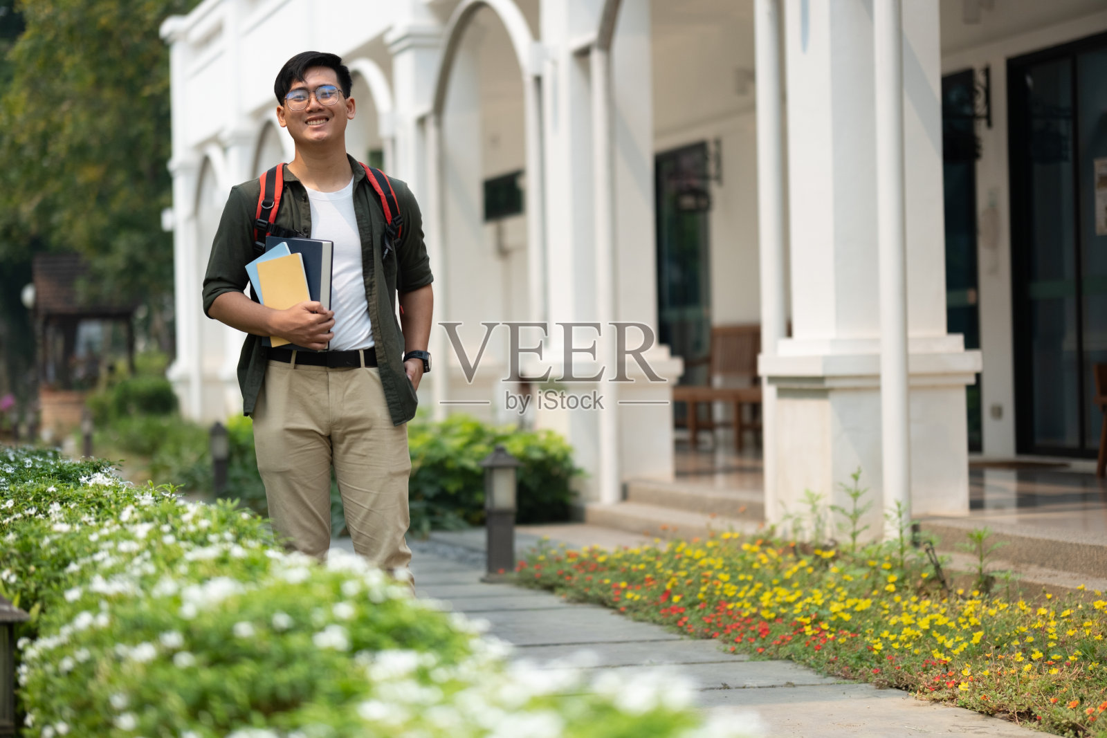 一个背着背包、戴着眼镜的年轻人走在人行道上照片摄影图片