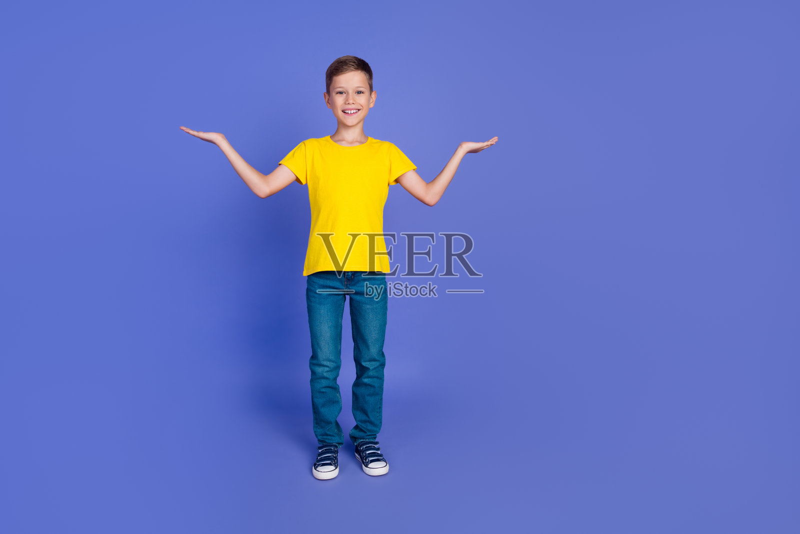 照片中开朗开朗的小男孩穿着时髦的黄色衣服，在紫色的背景上展示了孤立的空间照片摄影图片