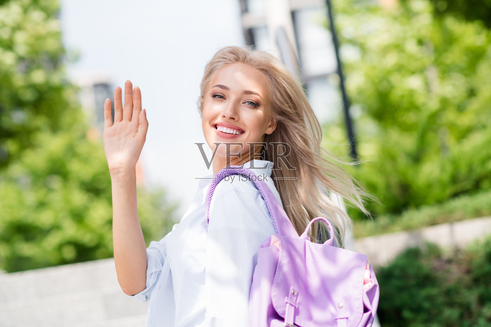 阳光明媚的一天，可爱的女孩走在绿色的公园里，挥舞着手臂，你好，好心情的春天照片摄影图片