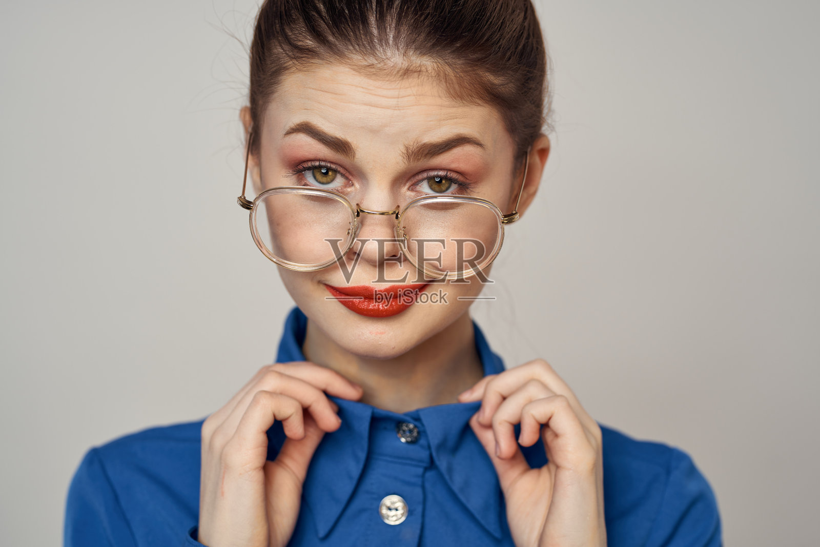 情绪化的女人在蓝色衬衫和眼镜的肖像明亮的化妆模型光背景裁剪视图复制空间照片摄影图片