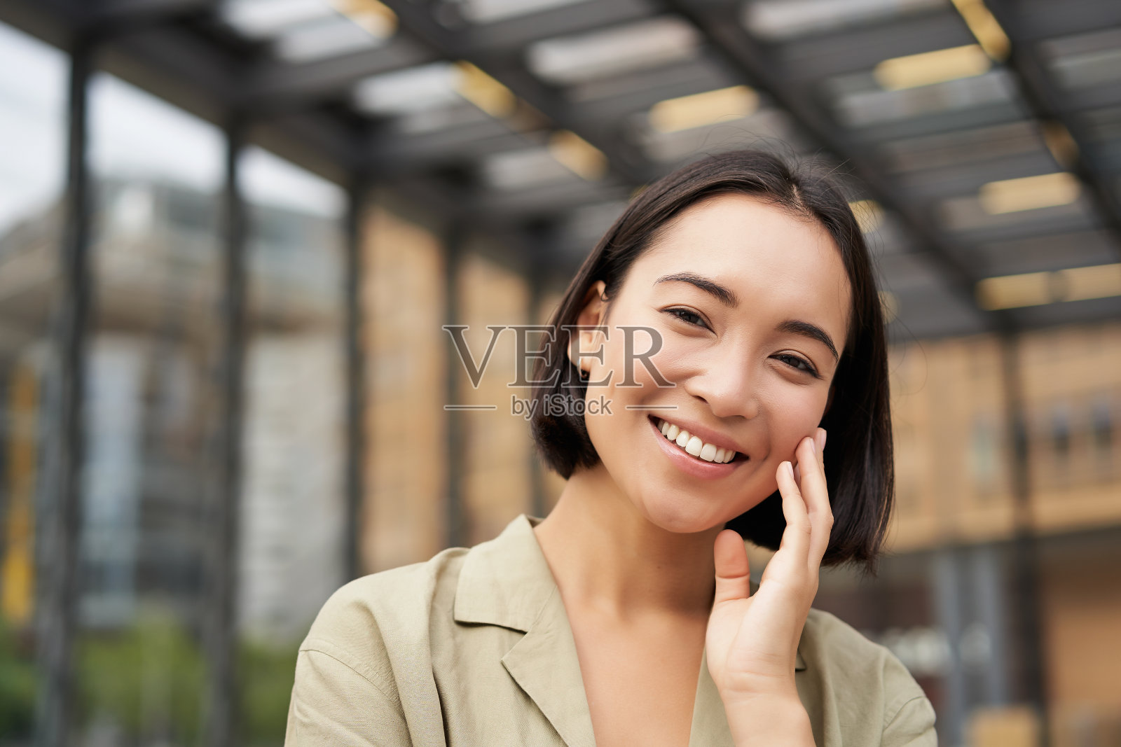 亚洲女孩的近距离肖像与幸福的脸，微笑和大笑，触摸她的皮肤，站在街上在阳光明媚的一天照片摄影图片