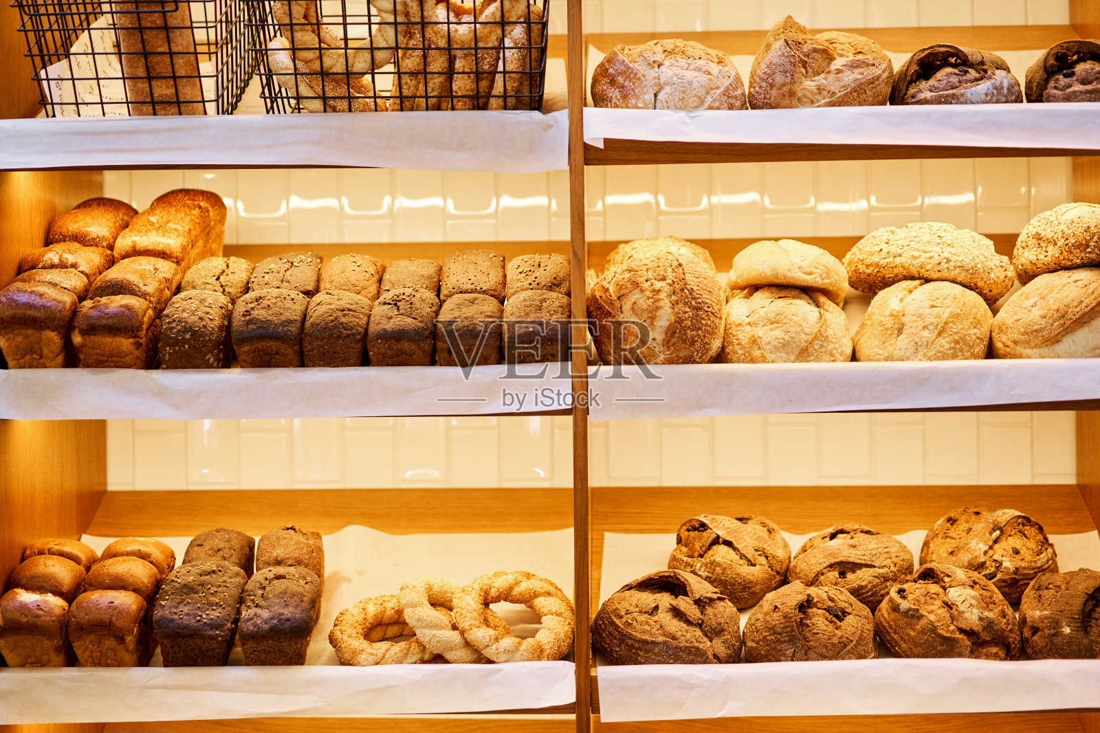 面包店柜台上有各种各样的面包。新鲜面包柜台。现代面包店，有各种各样的面包、蛋糕和小圆面包照片摄影图片