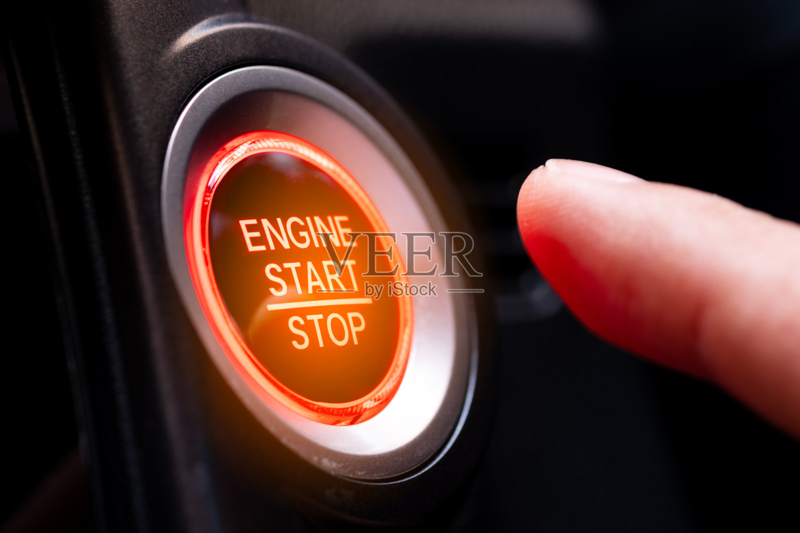 驾驶员的手正在按汽车启动按钮。交通和技术的概念照片摄影图片