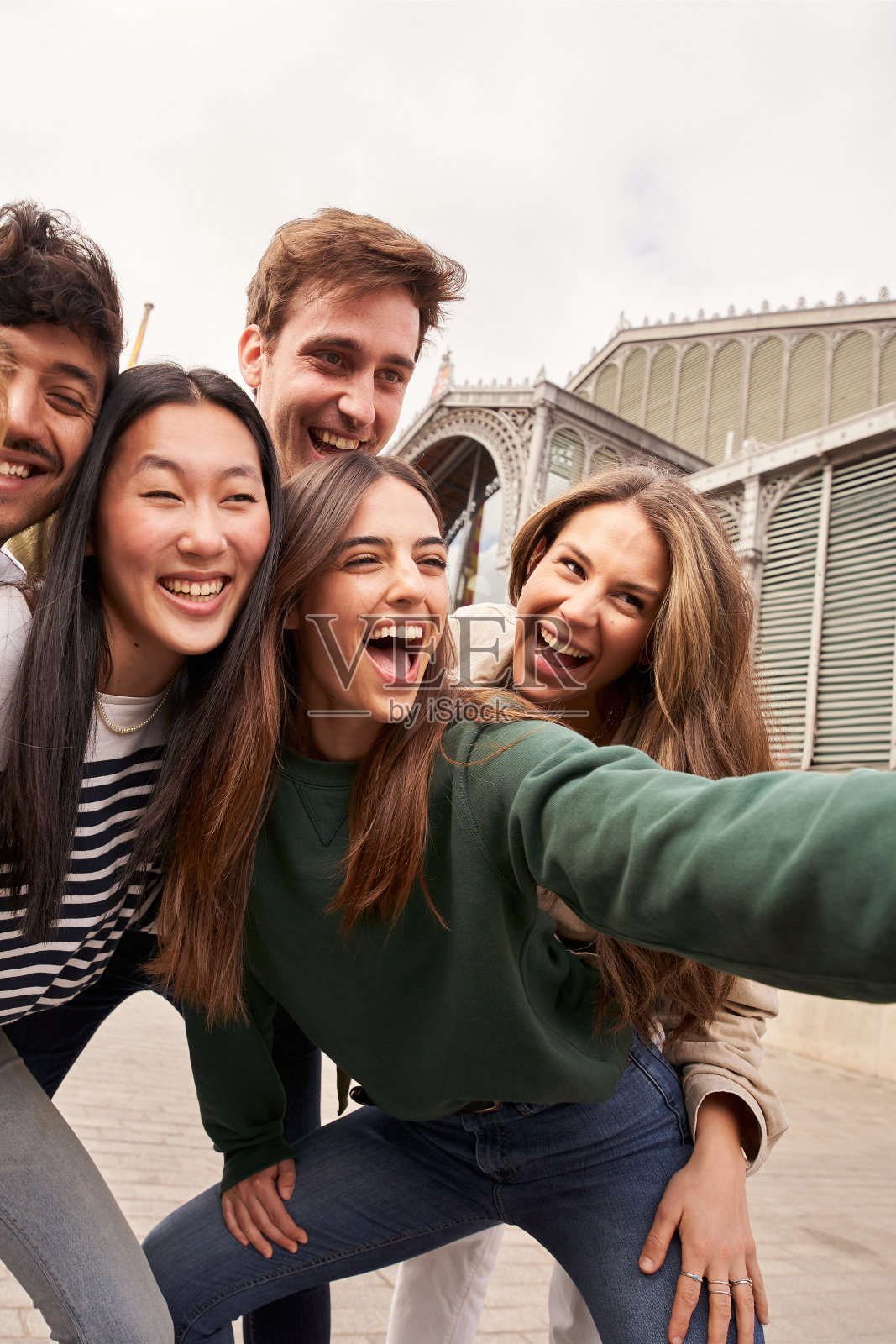 一群快乐的年轻人在旅游活动中微笑着做手势，一起自拍。照片摄影图片