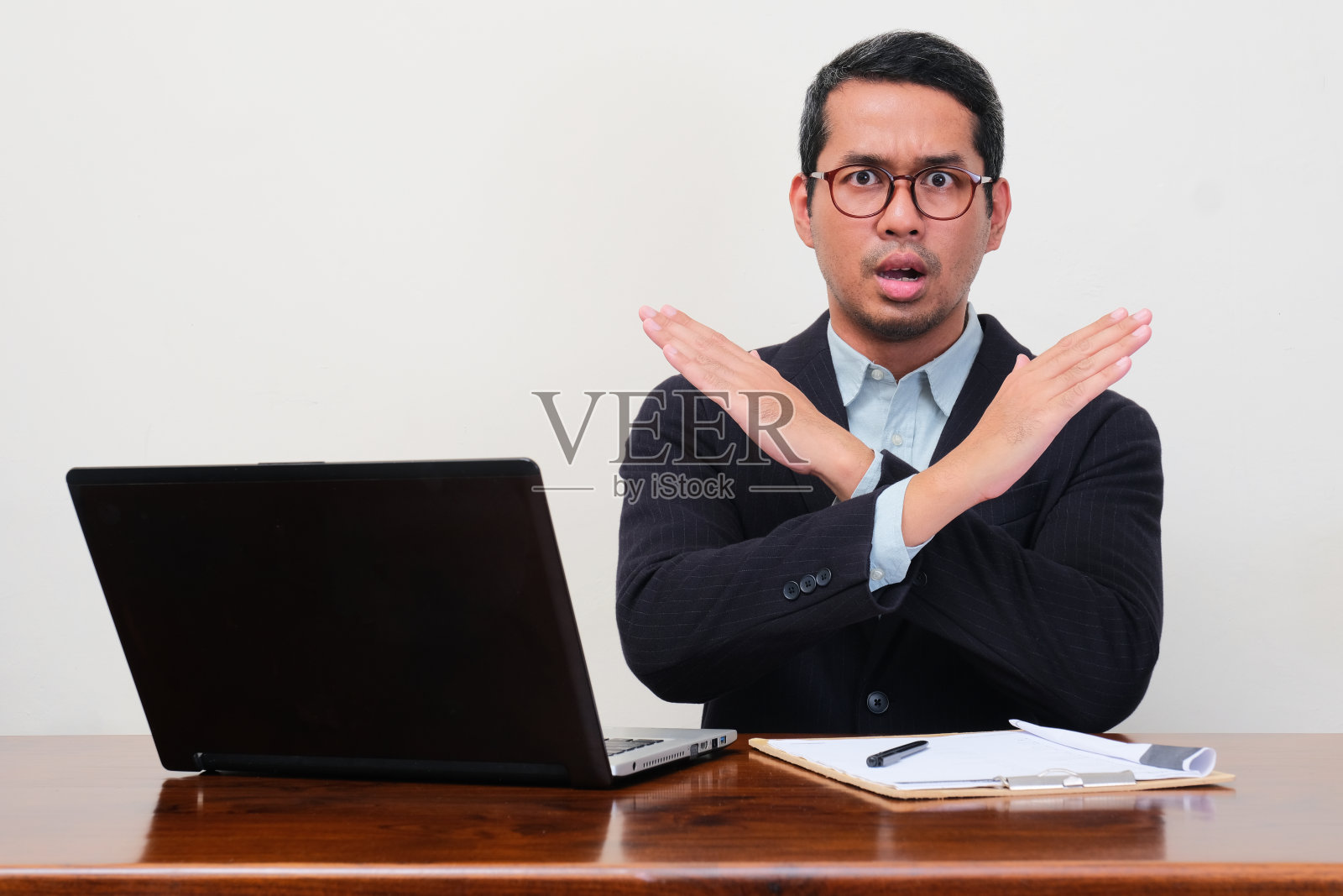 一位招聘人员坐在他的工作场所看着相机，并给出停止手势照片摄影图片