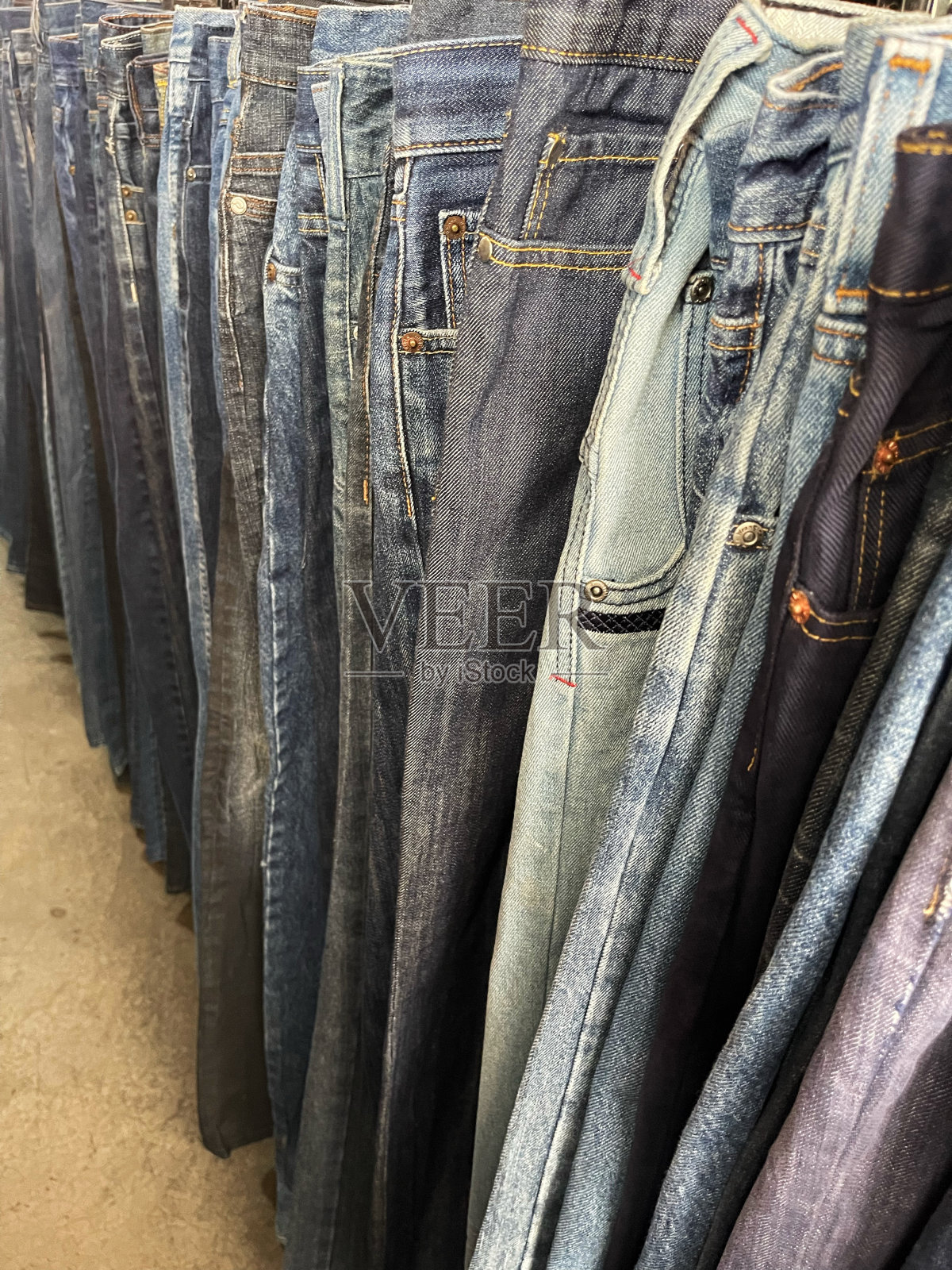 一排悬挂的旧牛仔裤在捆绑商店出售照片摄影图片