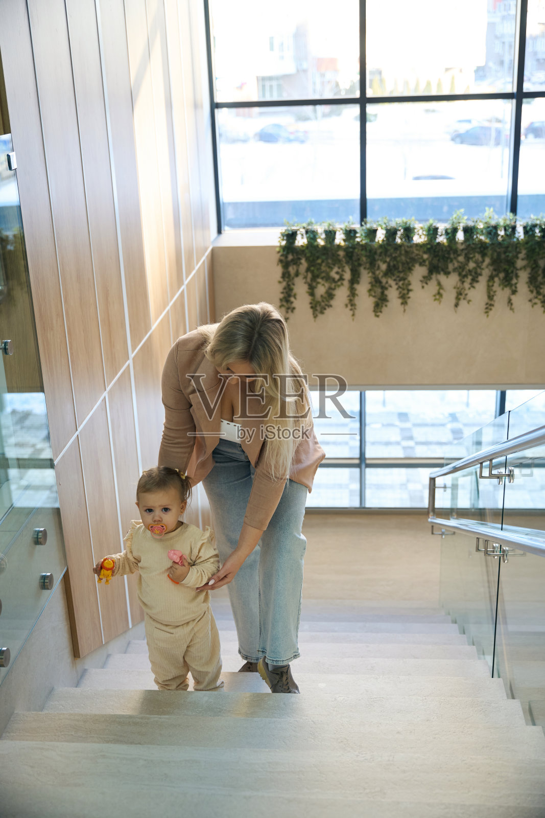 平静的孩子在母亲的帮助下爬上楼梯照片摄影图片