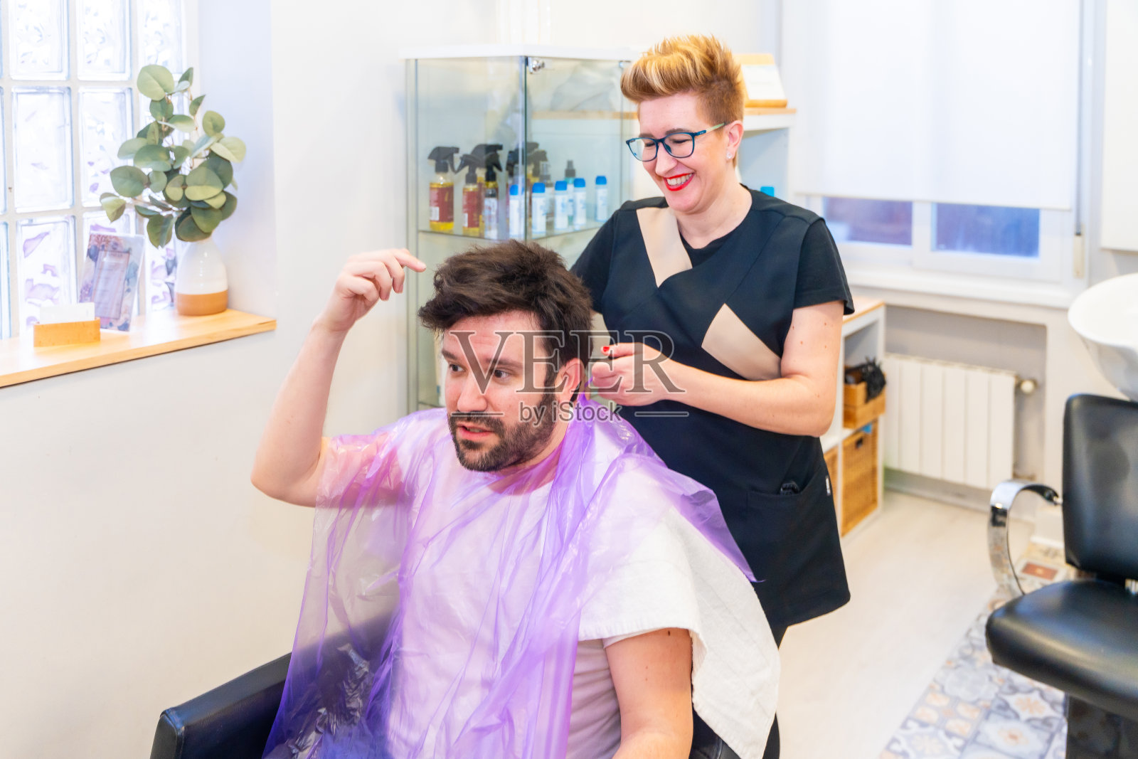 戴着毛细血管假体的男人和理发师聊天照片摄影图片