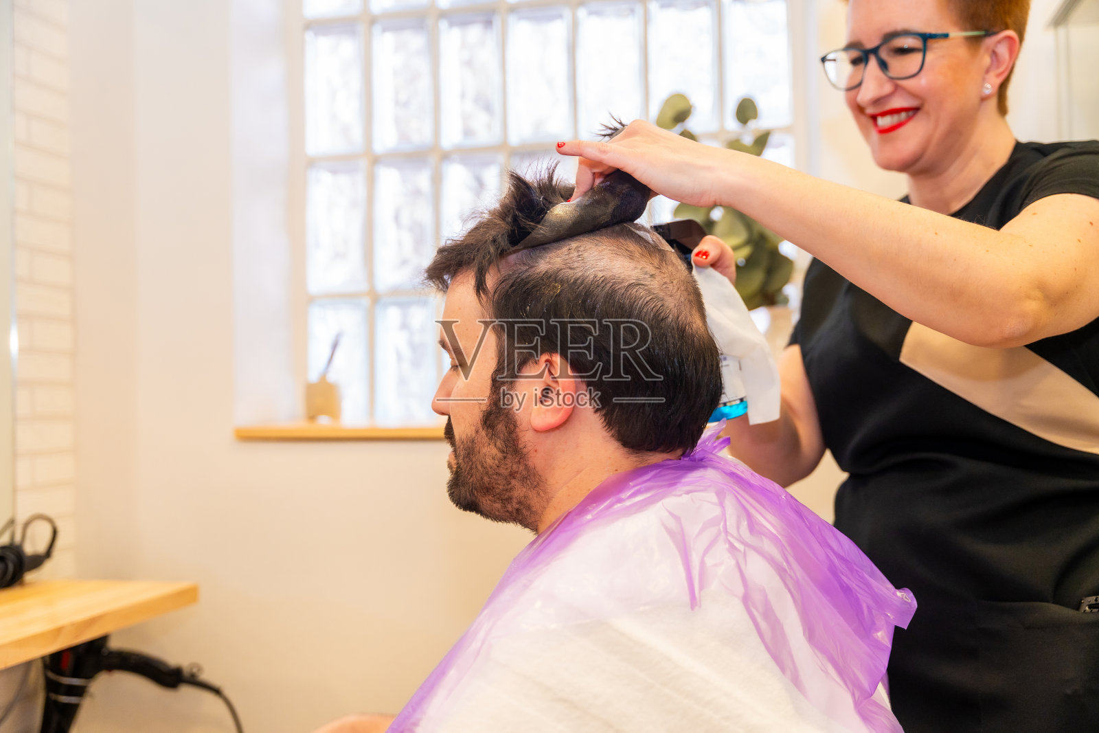 友好的理发师正在为客户小心地取出毛细假体照片摄影图片