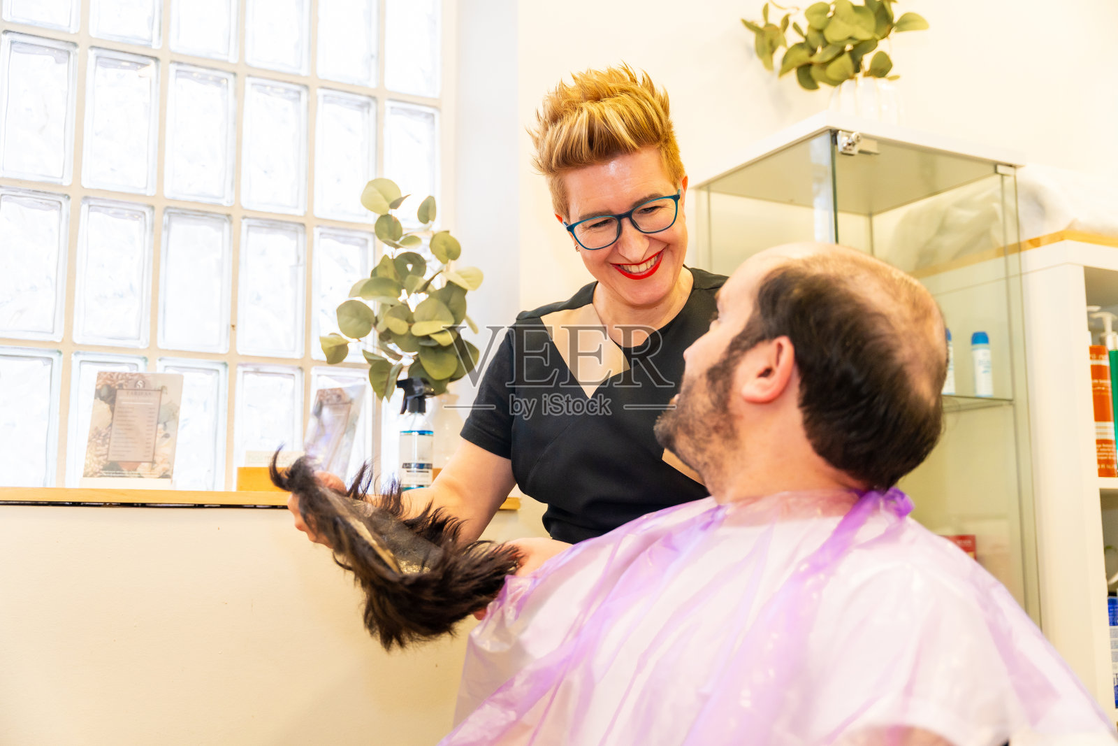 秃顶男子和发型师在取毛管假体时交谈照片摄影图片