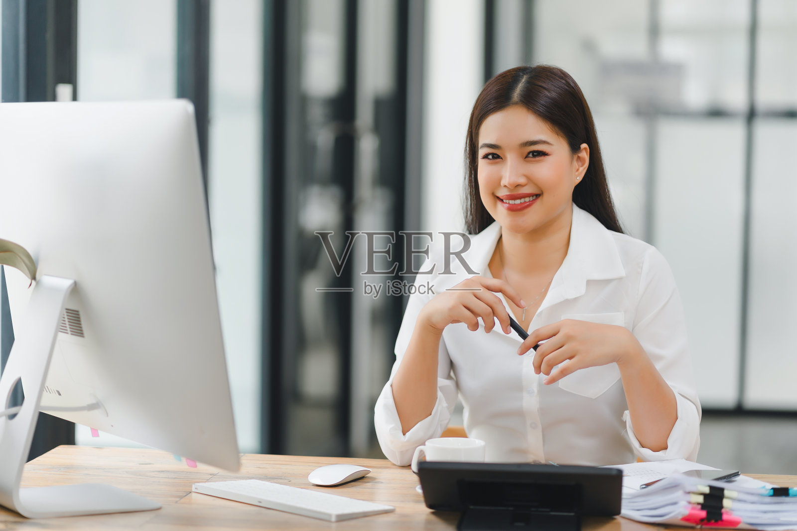 专业的亚洲女商人在现代办公环境中坐在办公桌前工作。照片摄影图片