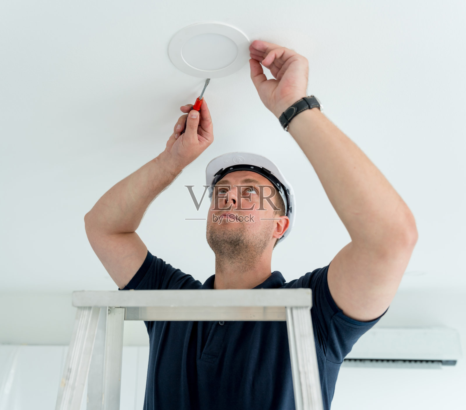 技术人员正在天花板上安装LED聚光灯。照片摄影图片