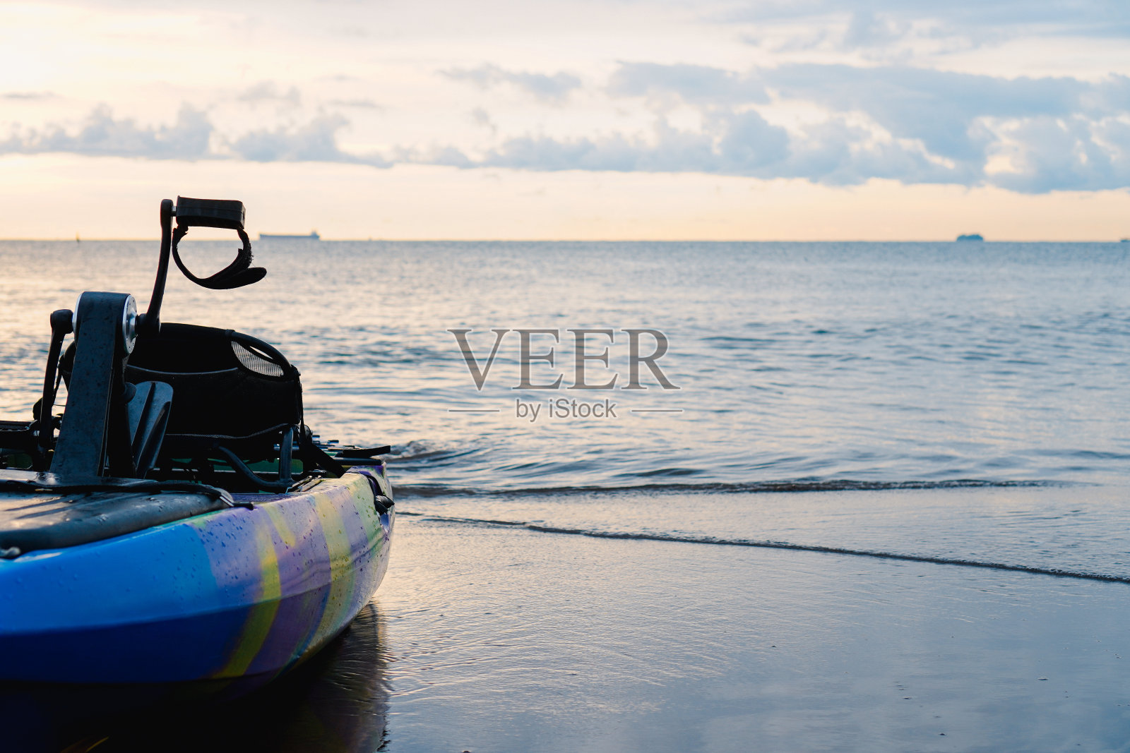 在沙滩上被冲上岸的蓝色皮艇。蓝天上的白云。在近海水域的背景中照片摄影图片