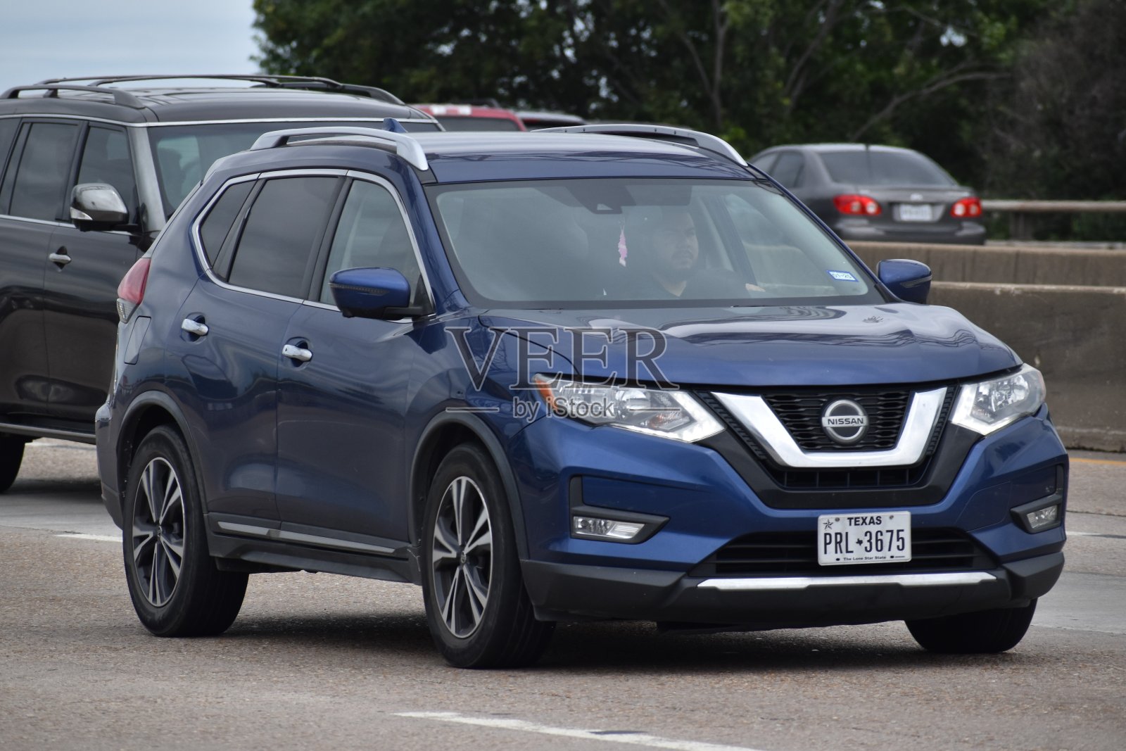 一辆蓝色的尼桑Rogue SUV行驶在中等交通的高速公路上照片摄影图片