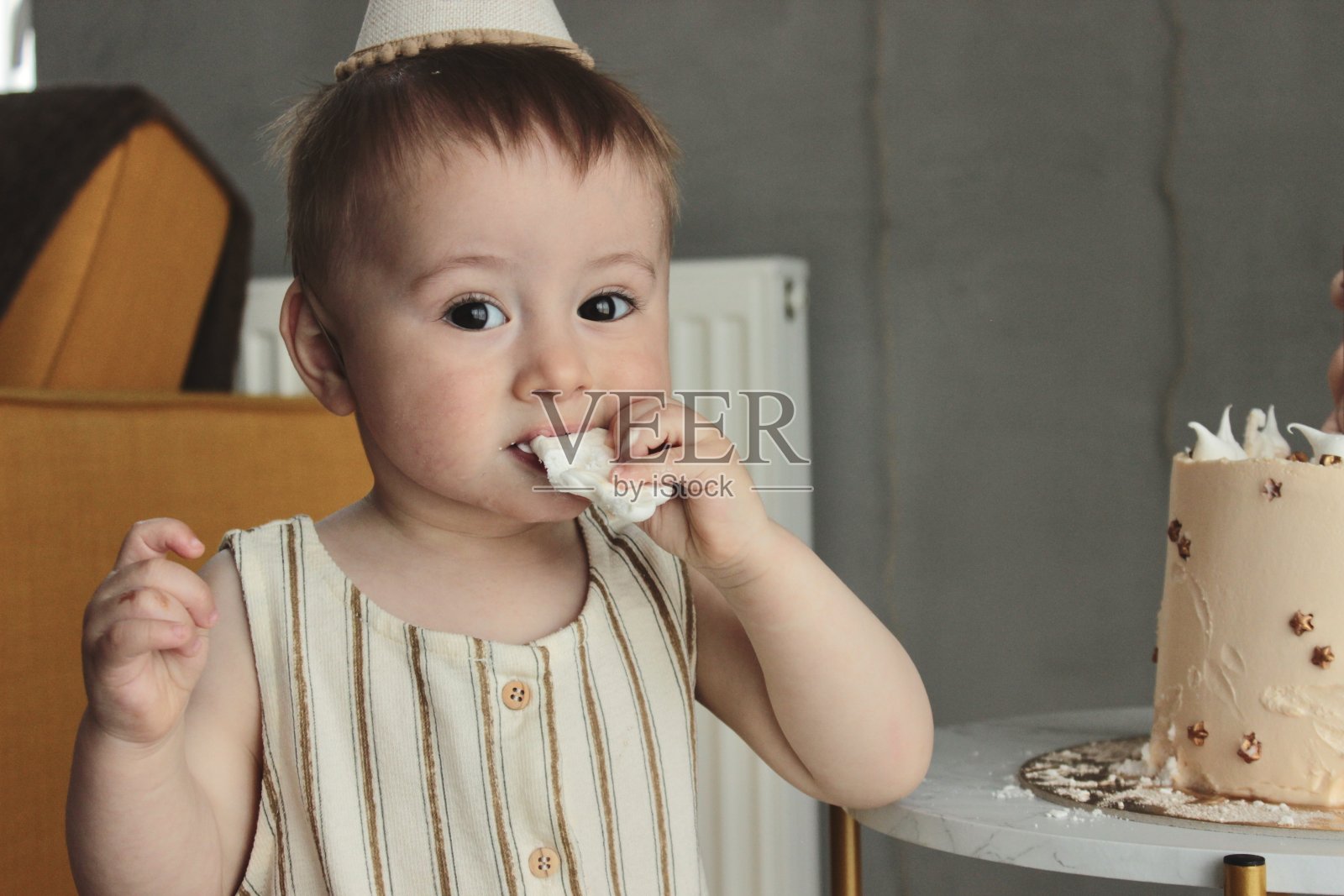 一个戴着帽子的小寿星品尝生日蛋糕照片摄影图片