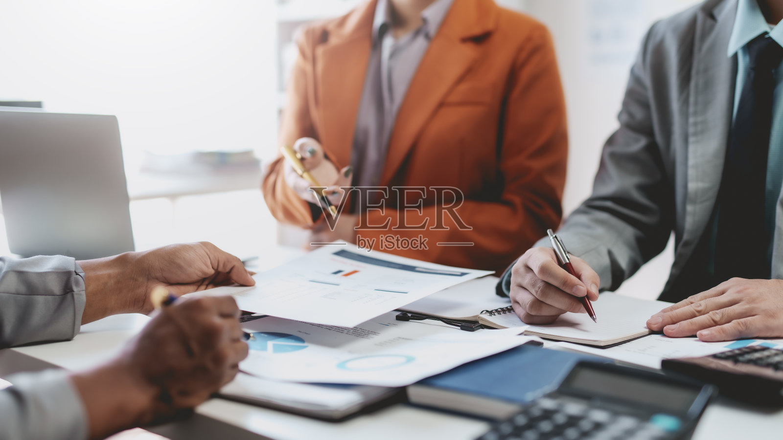 商务人士指着图表开会。在会议上一起讨论的一群商人。照片摄影图片