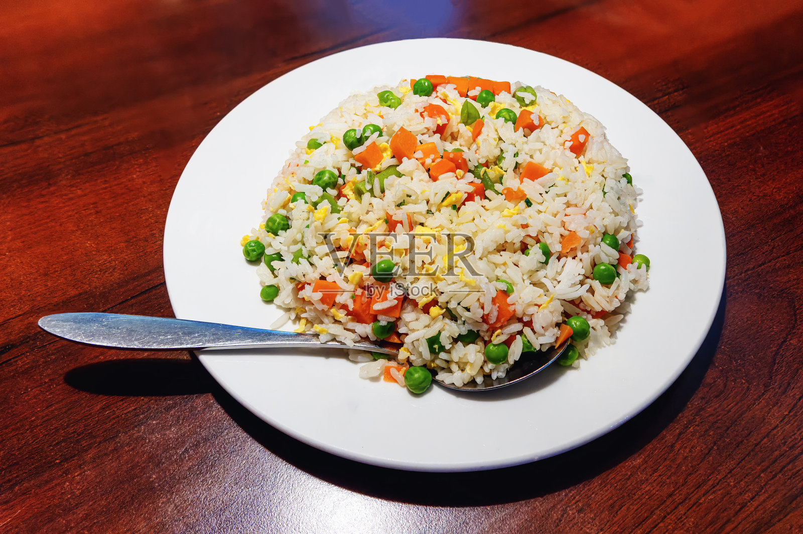 桌上的白色盘子里放着五颜六色的蔬菜拌饭照片摄影图片